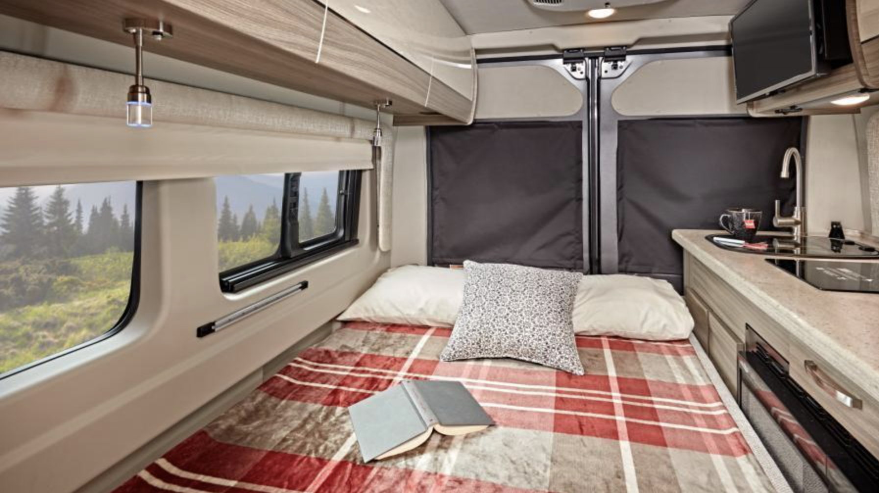 Cozy RV rental interior: bed with a plaid blanket, kitchen, and scenic window views of nature.. Entegra Coach Ethos 2023