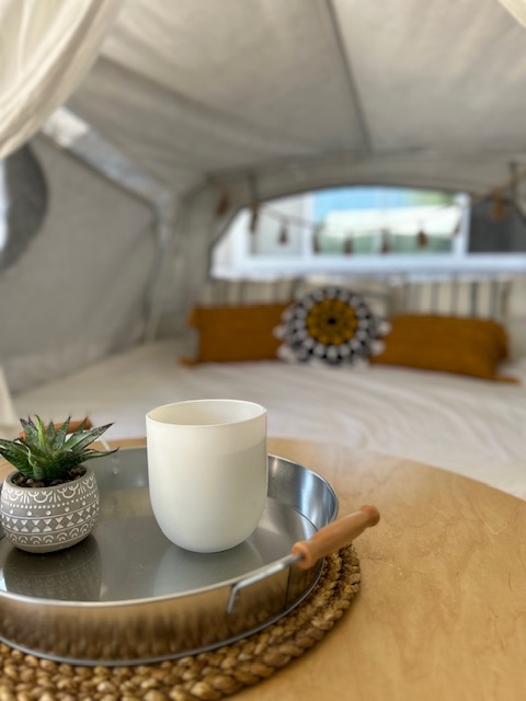 Cozy RV rental interior: a comfy bed, tray with mug & succulent, set in a bright pop-up camper. Your next adventure!. Coleman Frontier 1993