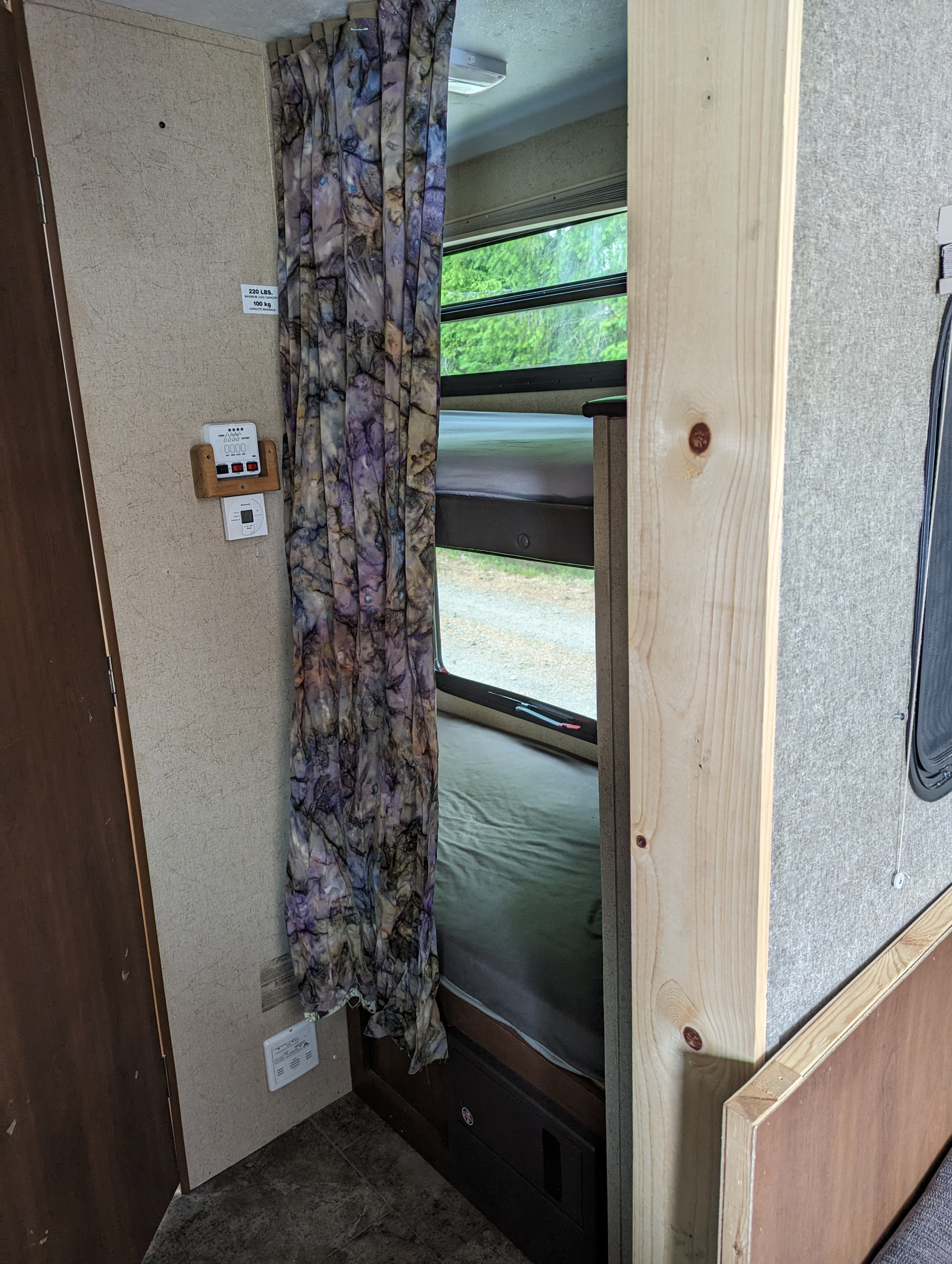 RV rental interior with bunk beds, a vibrant privacy curtain, window view, and wall-mounted controls.. Coachmen Freedom Express 2015