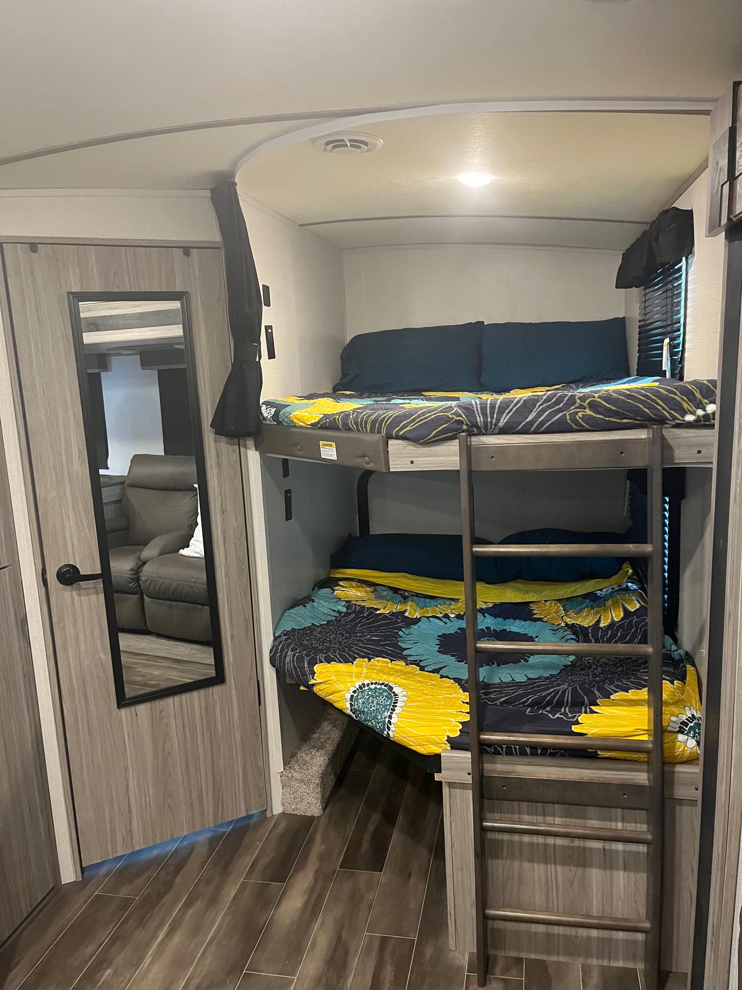Cozy bunk beds in an RV rental, featuring colorful bedding, a ladder, and mirrored door. Perfect for family trips!. Keystone RV Passport GT 2021