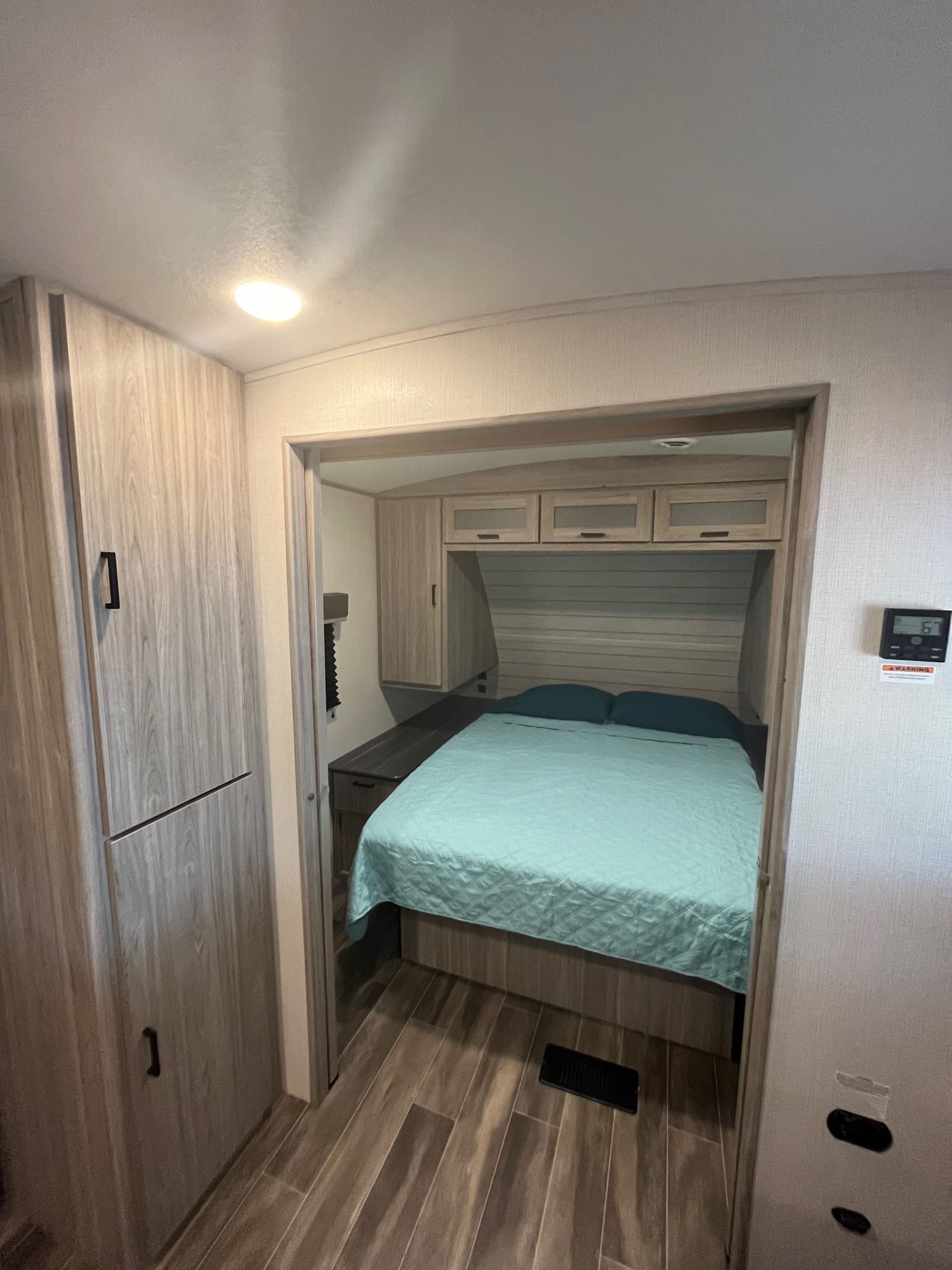 Spacious RV rental bedroom with a comfortable bed, light wood interior, and ample storage. Your cozy home on wheels.. Keystone RV Passport GT 2021