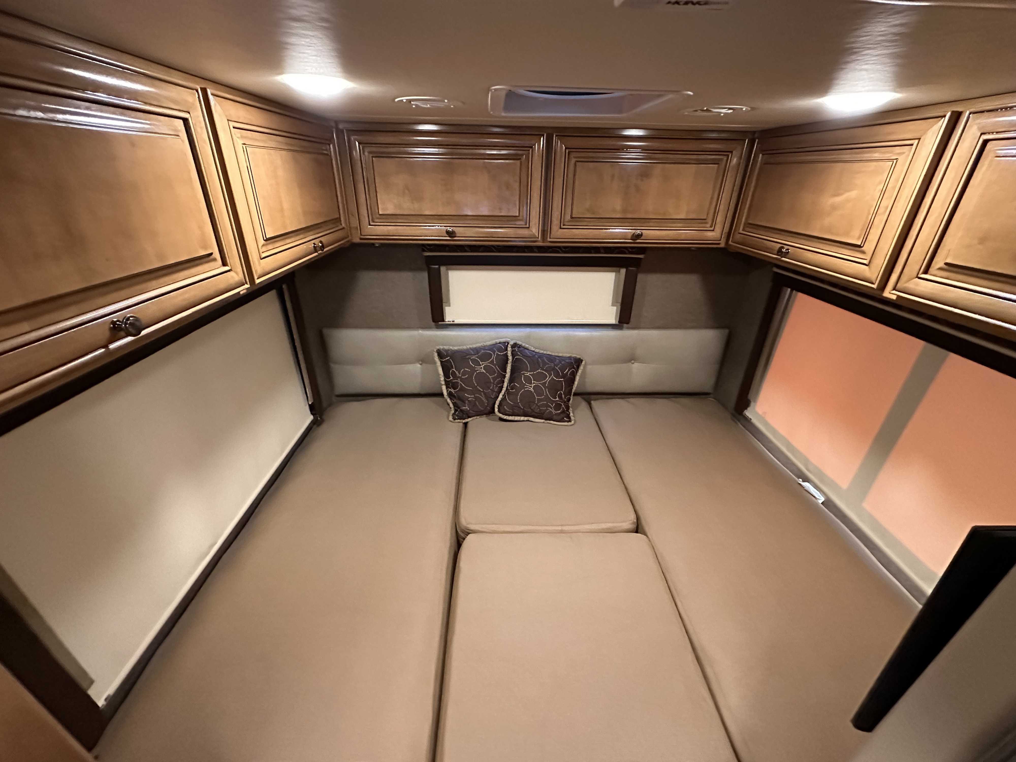 Cozy RV rental bedroom with wooden cabinets, a padded headboard, and modular bed cushions for comfort.. Thor Synergy 2016