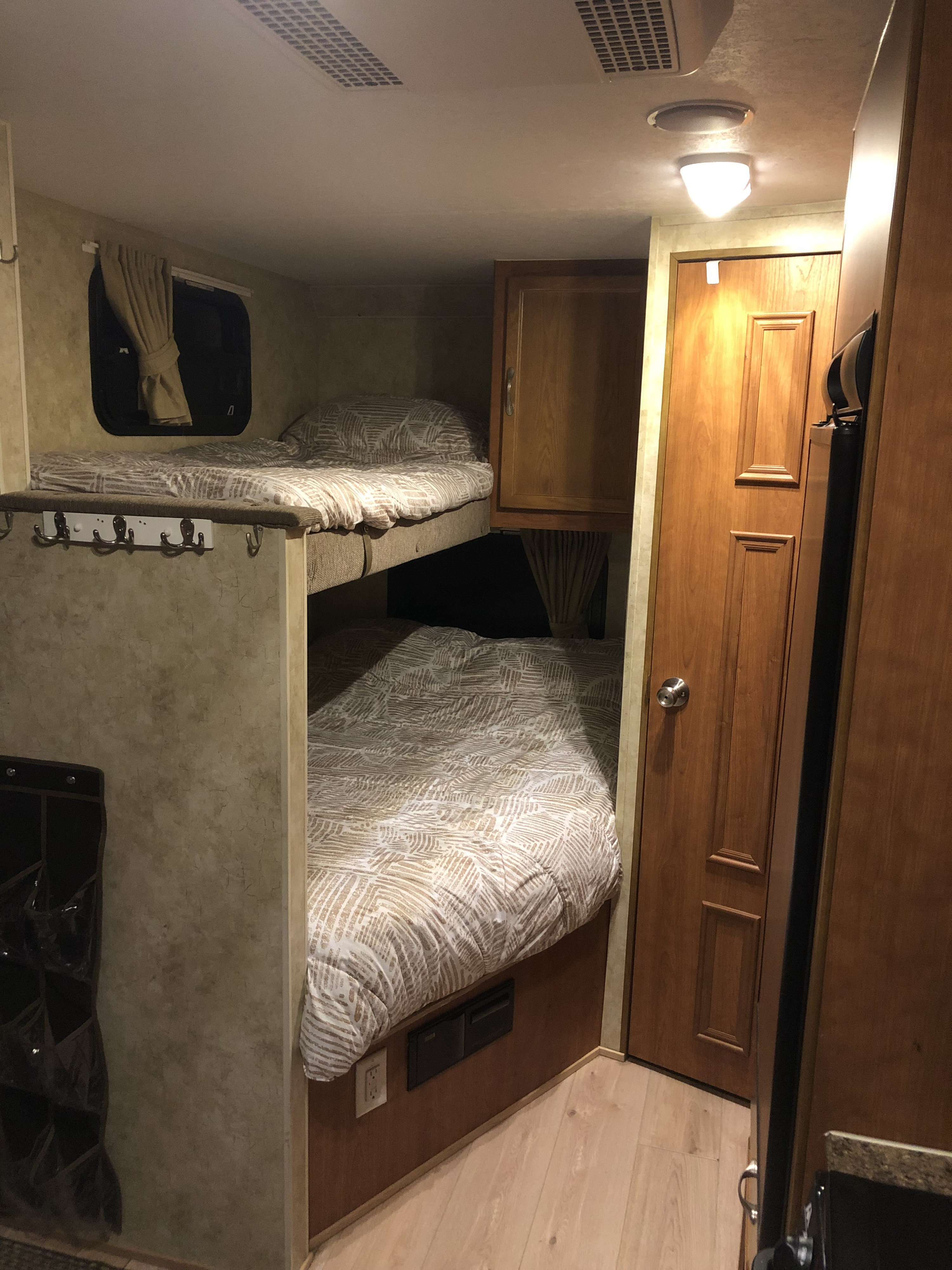 Cozy RV rental interior: a compact sleeping area with comfortable bunk beds, patterned bedding, and a window with curtain.. Starcraft Travel Star Sport 2010