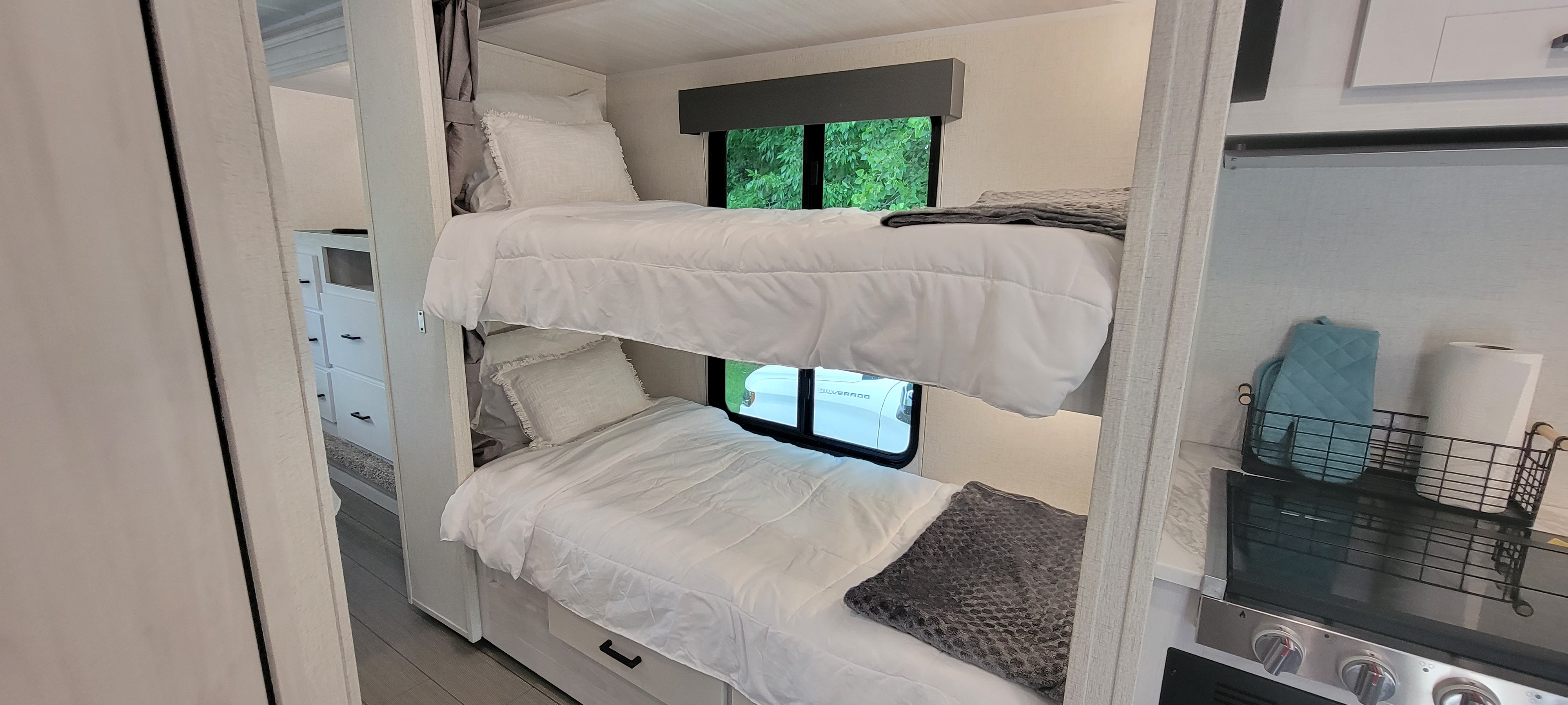 Explore this RV rental's interior: well-made bunk beds, bright linens, and a functional kitchen space visible.. East to West Entrada 2023