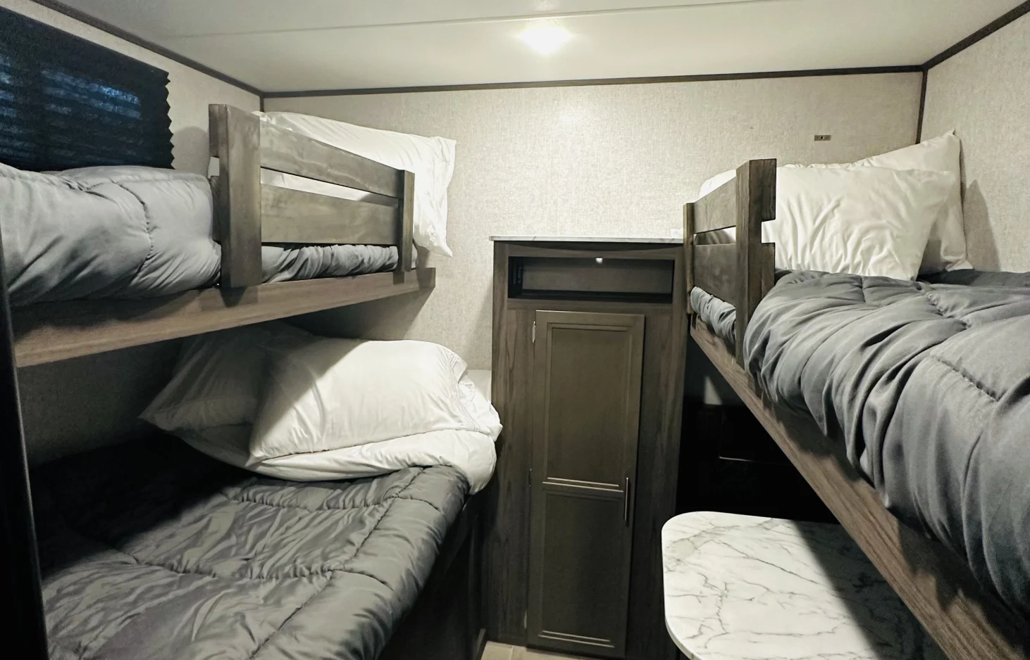 This RV rental features a cozy bunk room with two sets of beds, complete with grey comforters and white pillows.. Dutchmen Kodiak Ultra Lite 2021