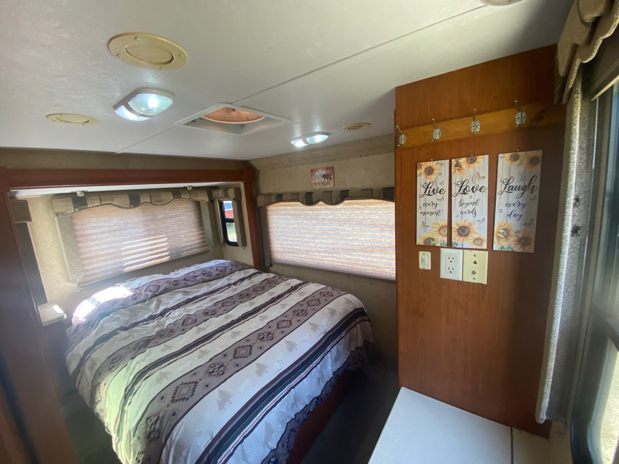 Cozy RV rental bedroom features a comfortable bed, warm sunflower decor, and windows, ideal for a relaxing trip.. Forest River Sunseeker 2010
