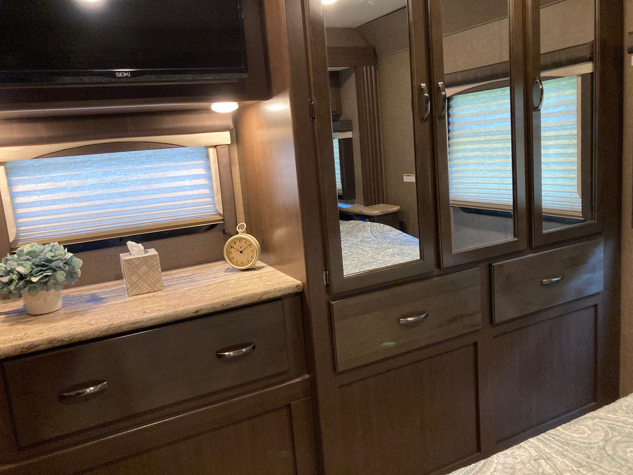 RV rental bedroom showcasing a TV, countertop, drawers, mirrored closet, and window blinds. Modern and functional space.. Thor A.C.E. 2017
