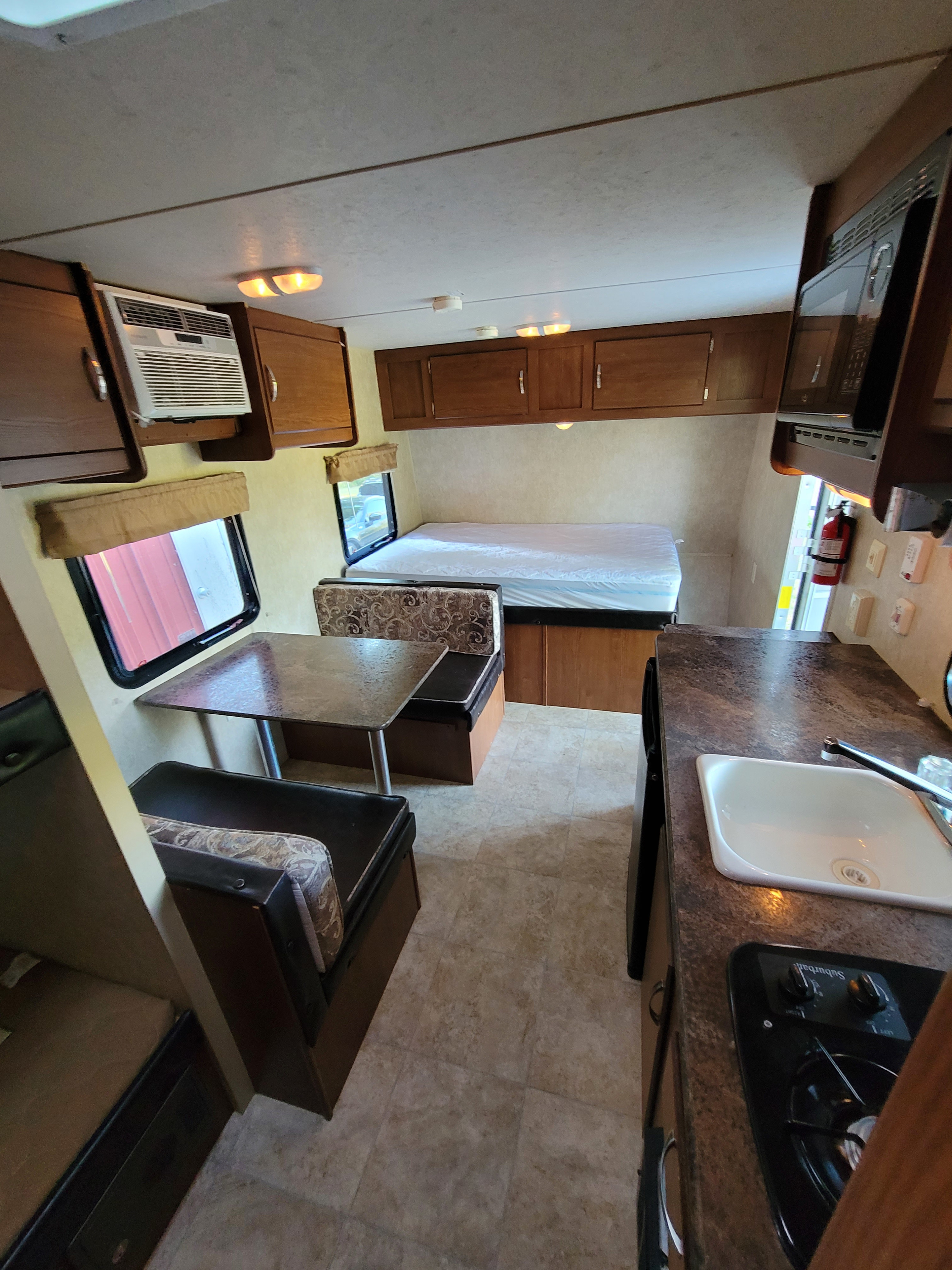 Cozy RV rental interior with a bed, dinette, and kitchen area, offering a comfortable space for travel and adventure.. Forest River Wildwood X-Lite 2014