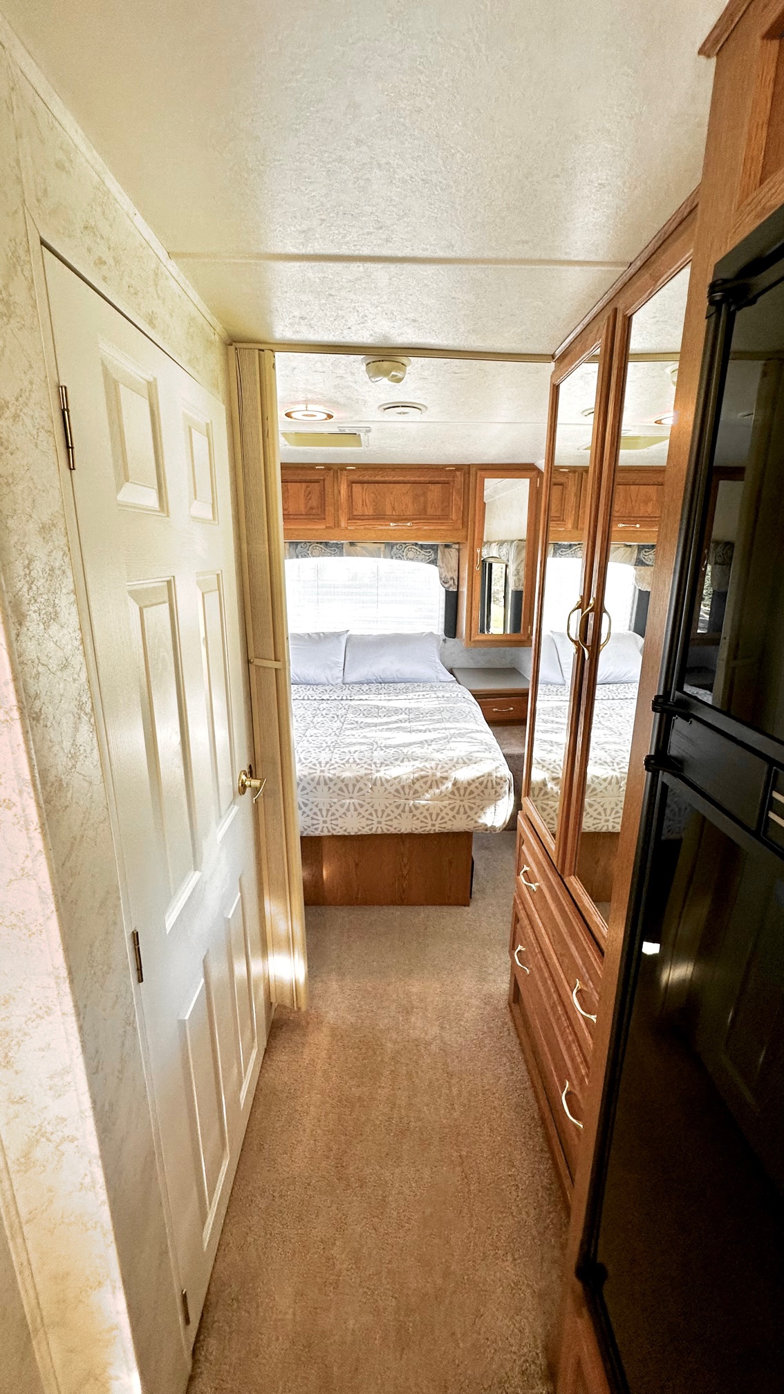 RV rental bedroom interior: cozy bed, wood cabinets, and mirrored wardrobe. Comfortable space for your travels.. Four Winds Hurricane 2002