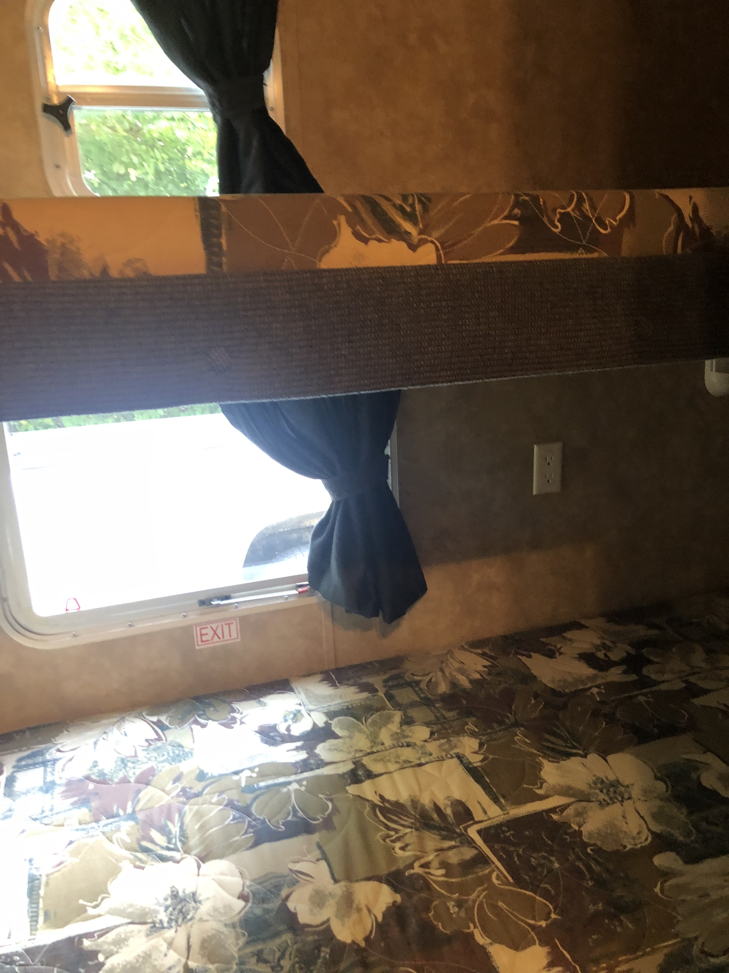 RV rental interior features bunk beds, bright windows with curtains, and an emergency exit sign for safety.. Jayco Jay Flight 2007