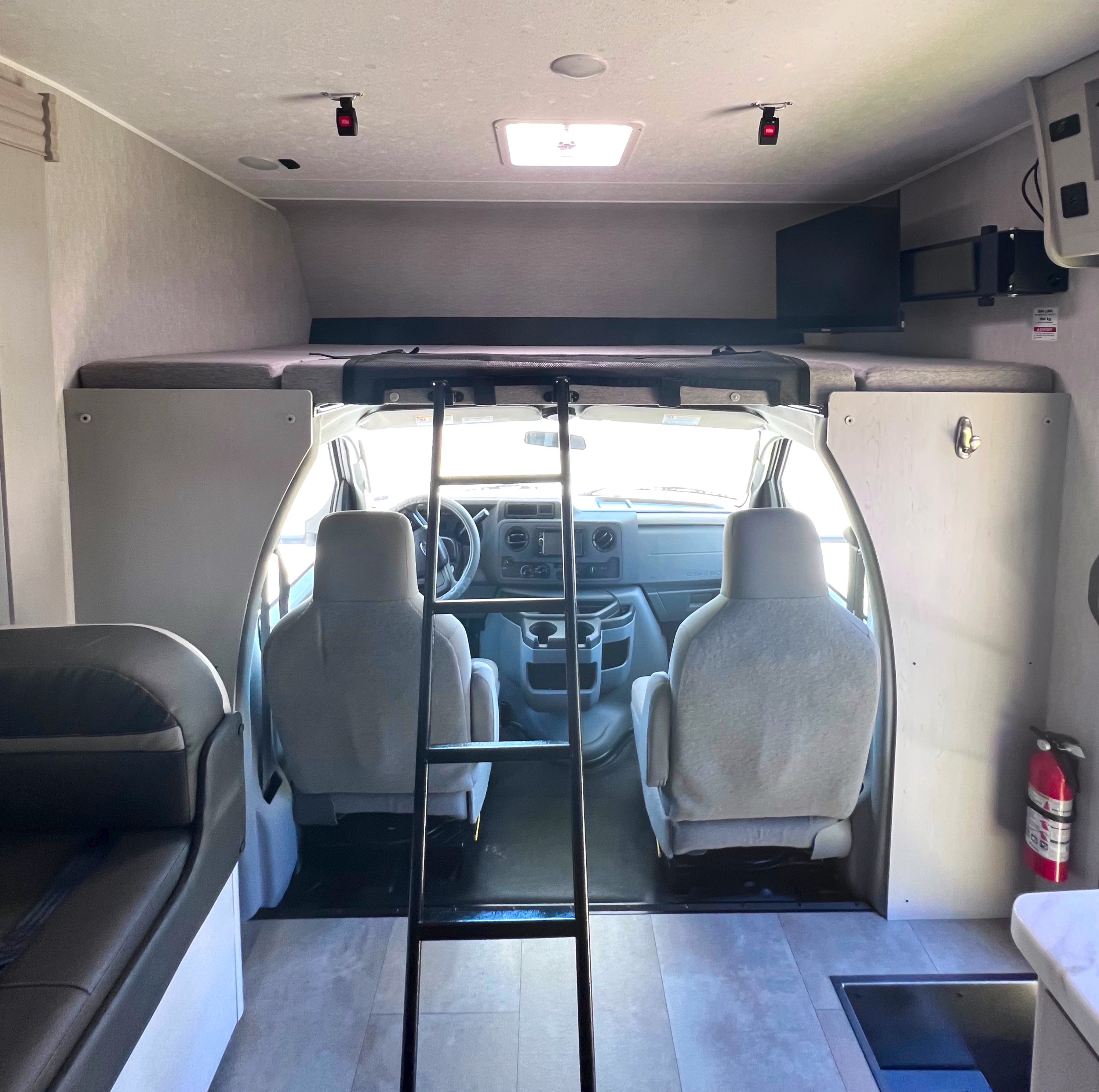 Interior of an RV rental, showcasing the cab, overhead bunk with ladder, and front living space.. Forest River Coachmen Freelander 2023