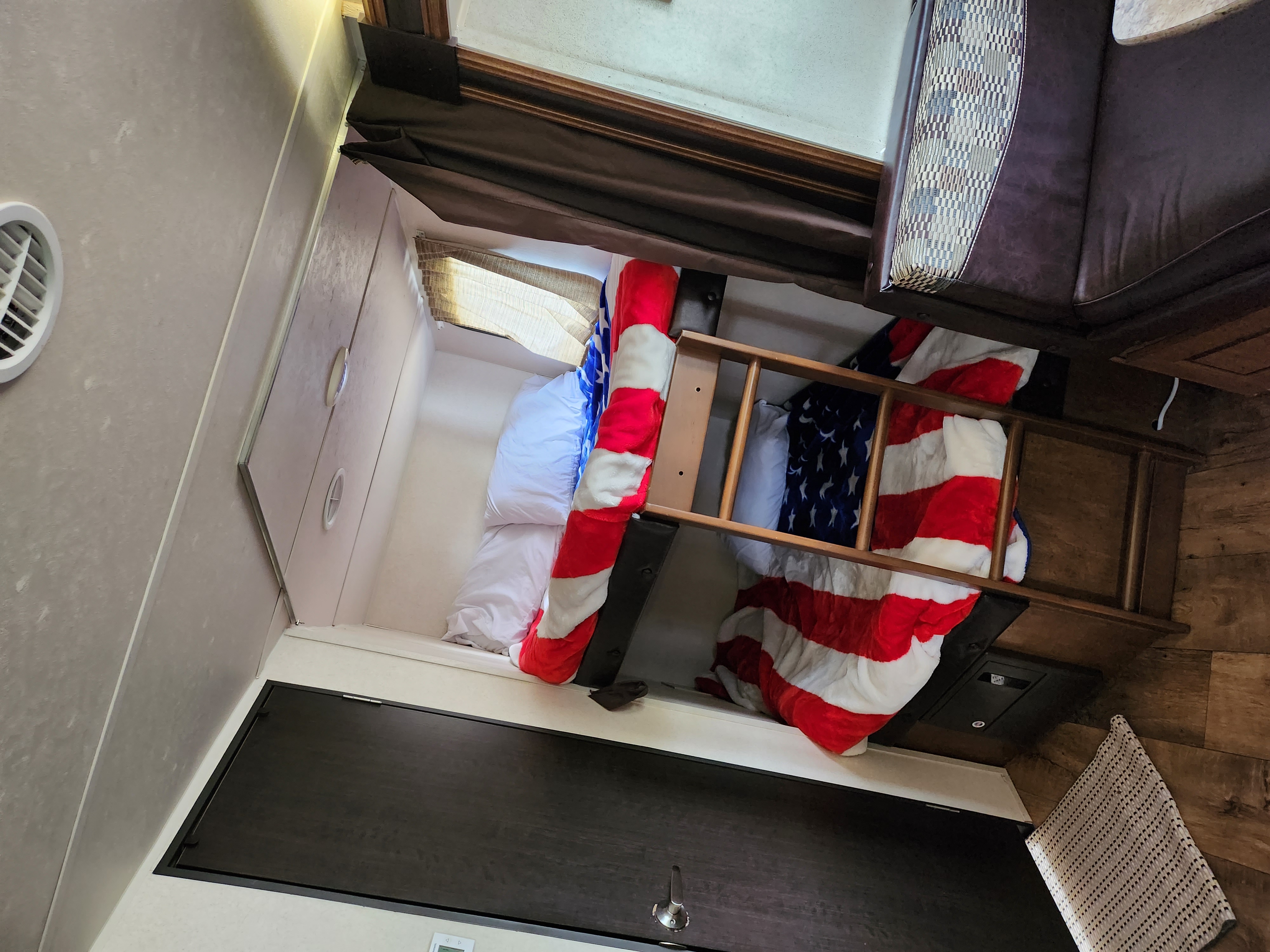 Cozy RV rental bunk beds with USA flag blankets & ladder, ideal for family travel.. Forest River Wildwood X-Lite 2017
