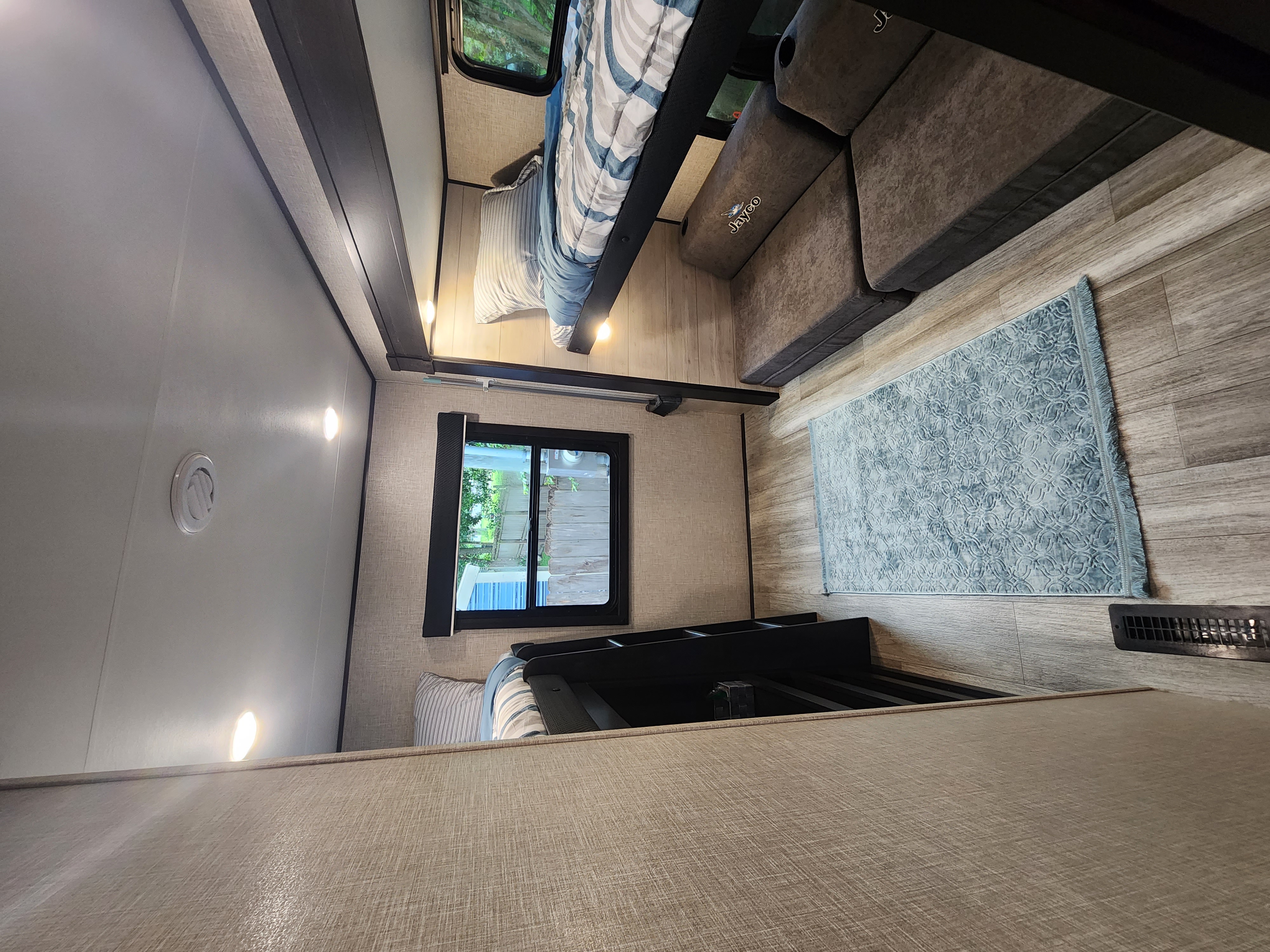 Cozy RV rental interior featuring bunk beds, a sofa, and wood-look flooring, ready for your next adventure.. Jayco Jay Flight 2023