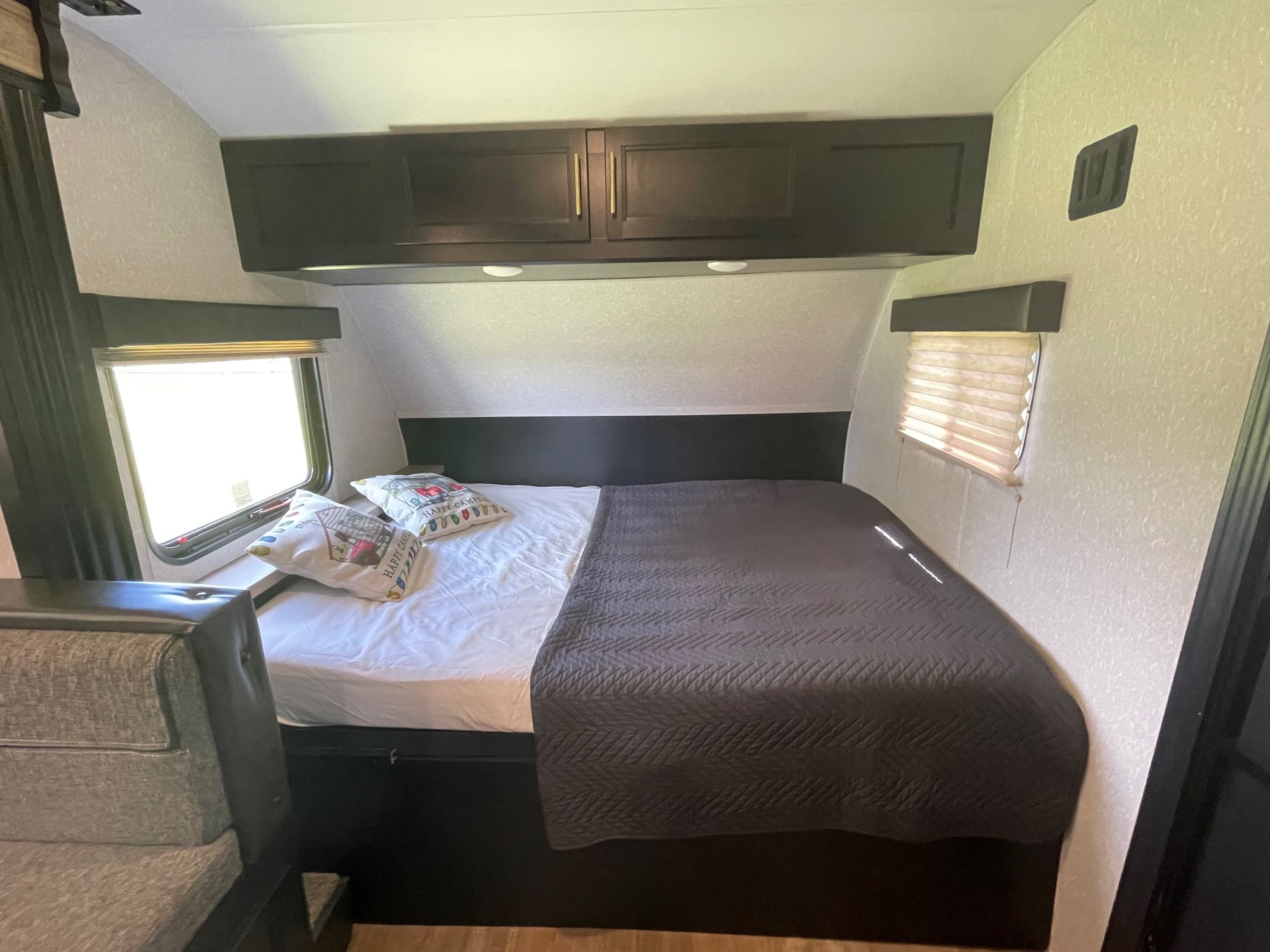Explore this cozy RV rental bedroom: queen bed with pillows, dark cabinets, and side windows for a comfy stay.. Forest River Cherokee Wolf Pup 2021