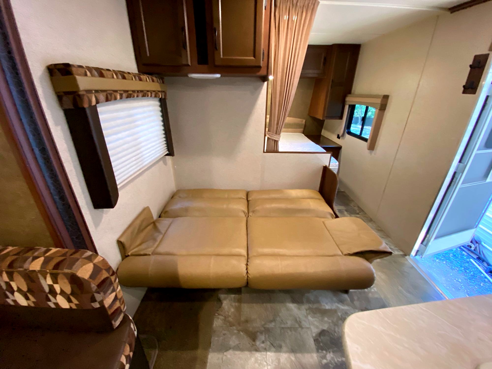 Inside this RV rental: a tan sofa bed, overhead storage, and bunk beds. Experience comfortable compact living on the road.. Jayco Jay Flight 2015