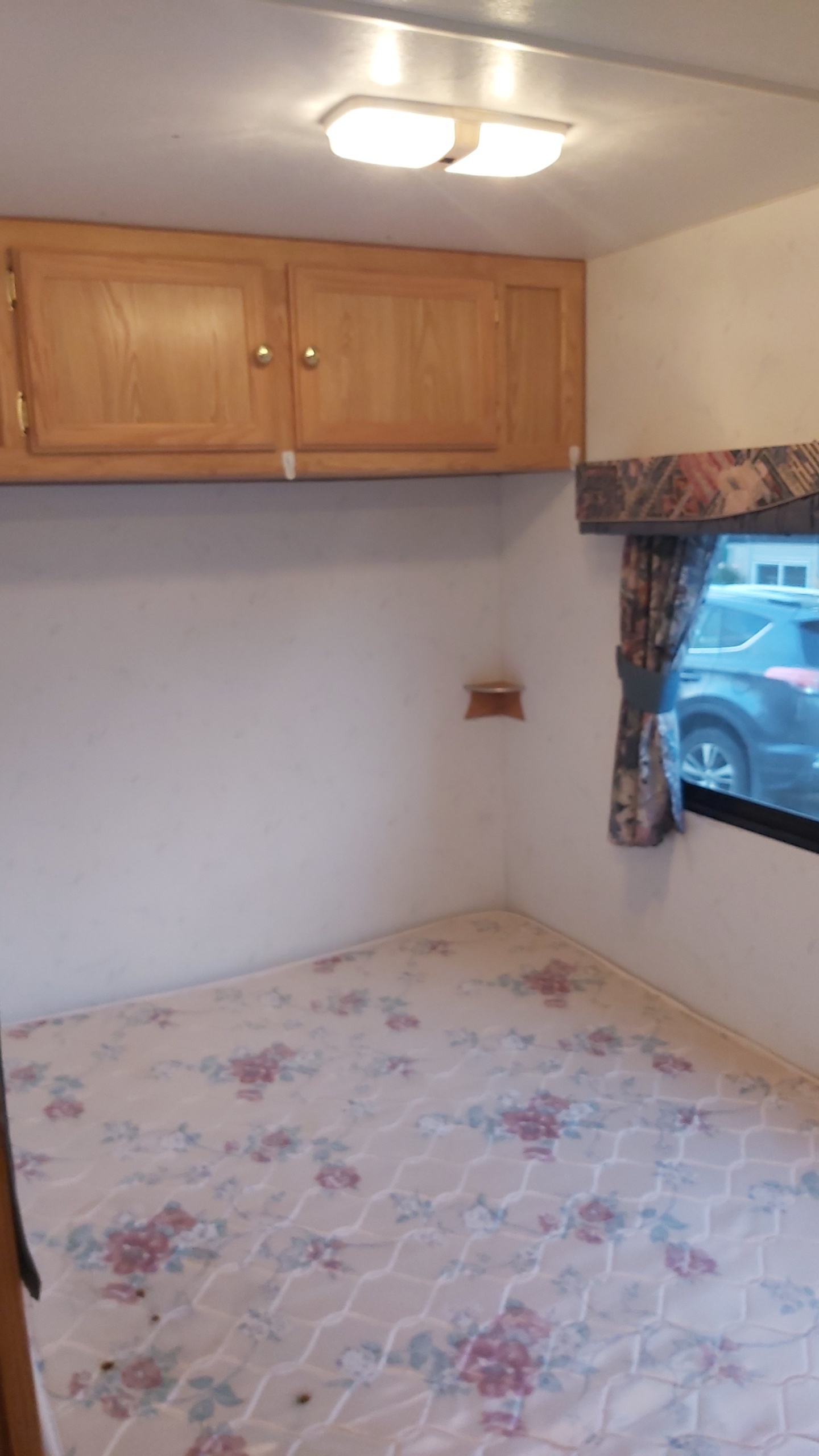Cozy RV rental bedroom with floral mattress, wood cabinets, and window view.. Kustom Koach Pt230 1998