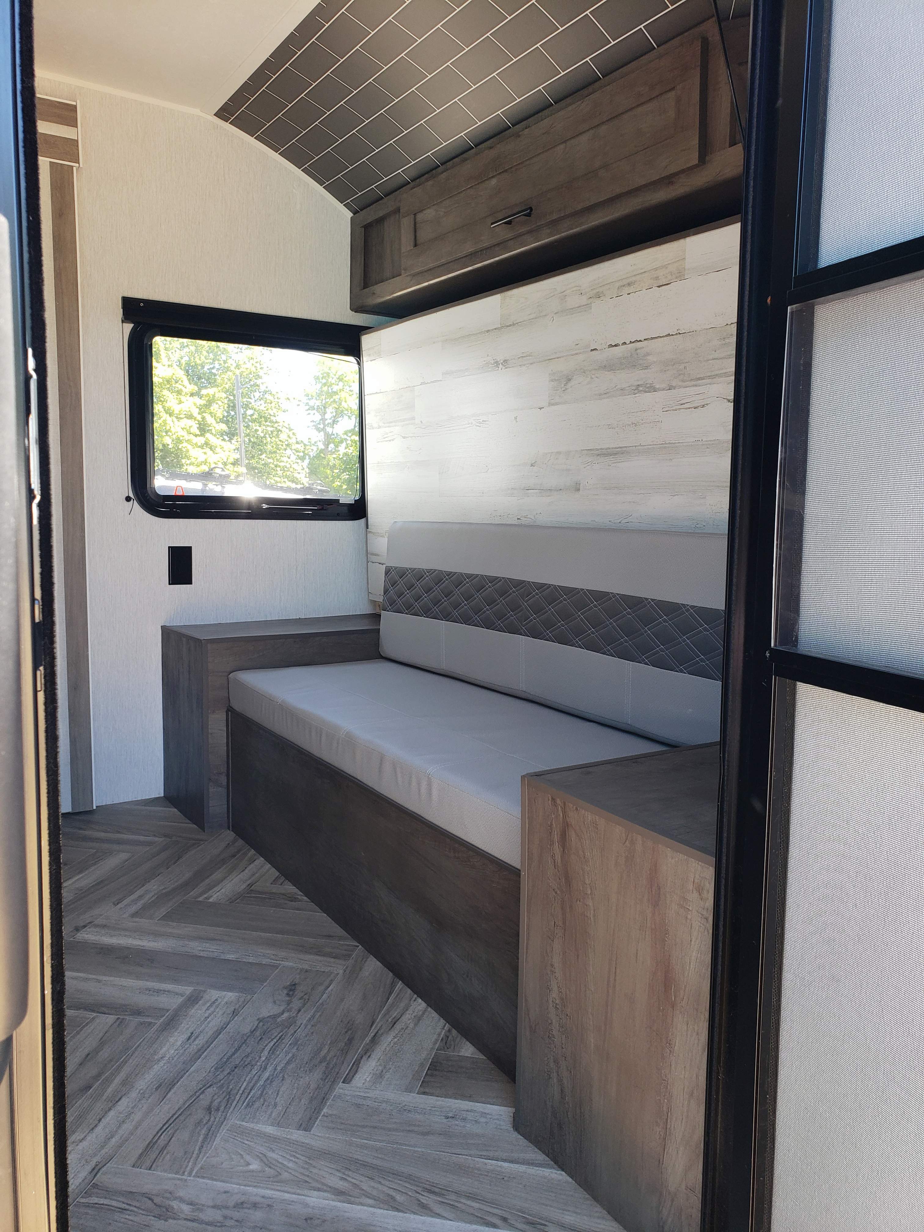 Modern RV rental interior with convertible bench seating, herringbone flooring, and sleek overhead storage.. Forest River Salem FSX 2022