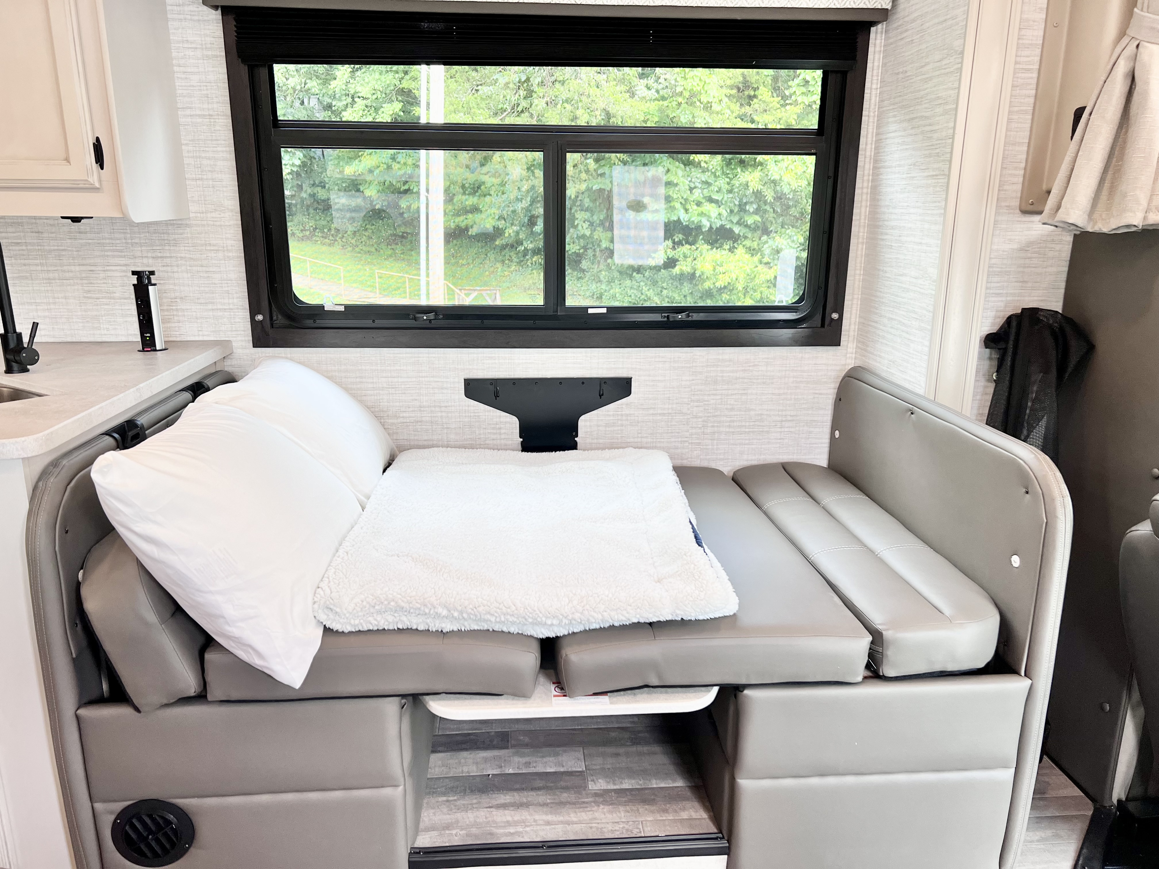 RV rental dinette easily converts to a cozy bed, featuring a scenic window, pop-up outlet & plush seating.. Jayco Redhawk 31F 2024