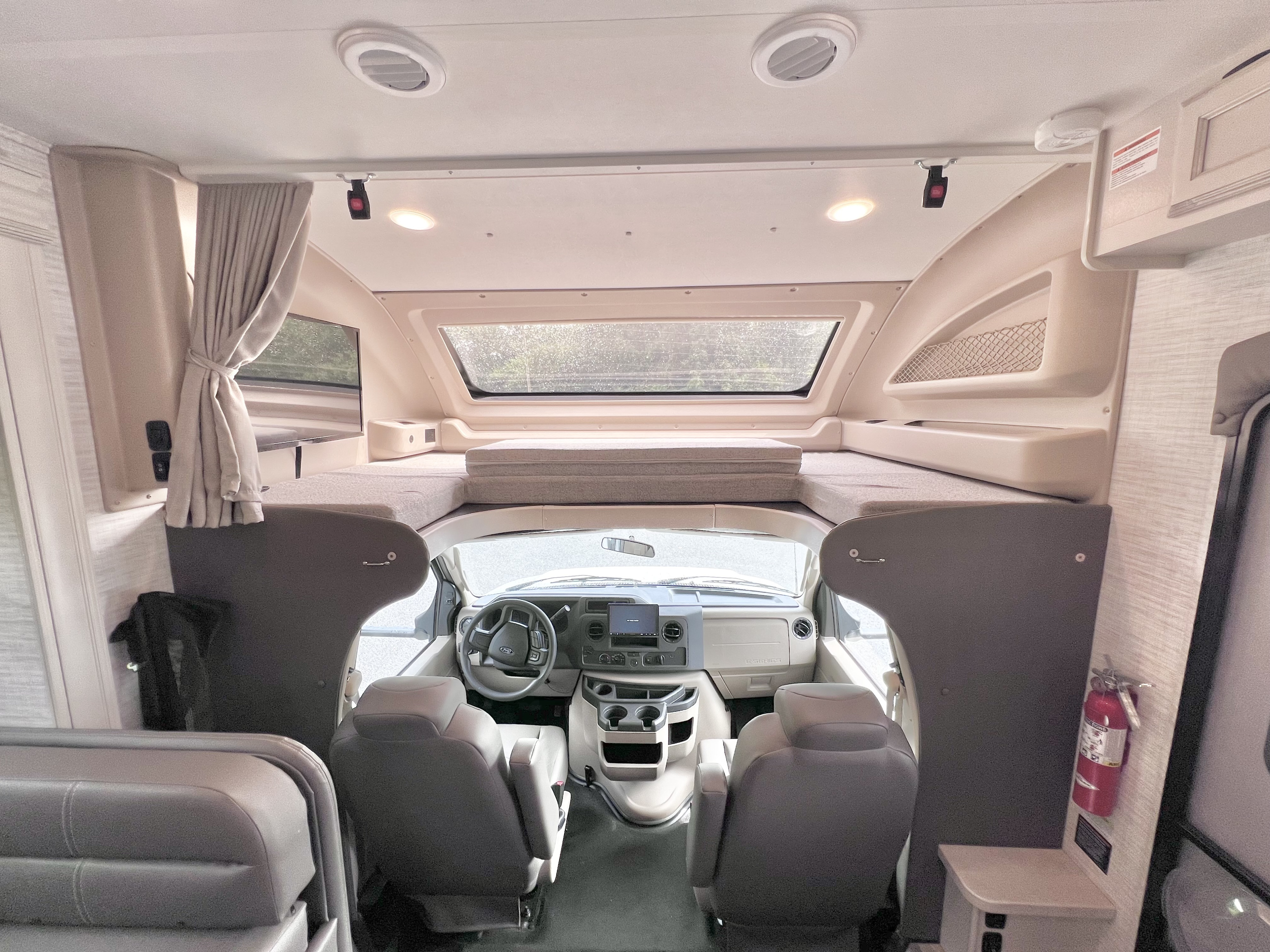Inside this spacious RV rental, a bright cockpit with a steering wheel and dashboard leads to a large cab-over bed.. Jayco Redhawk 31F 2024