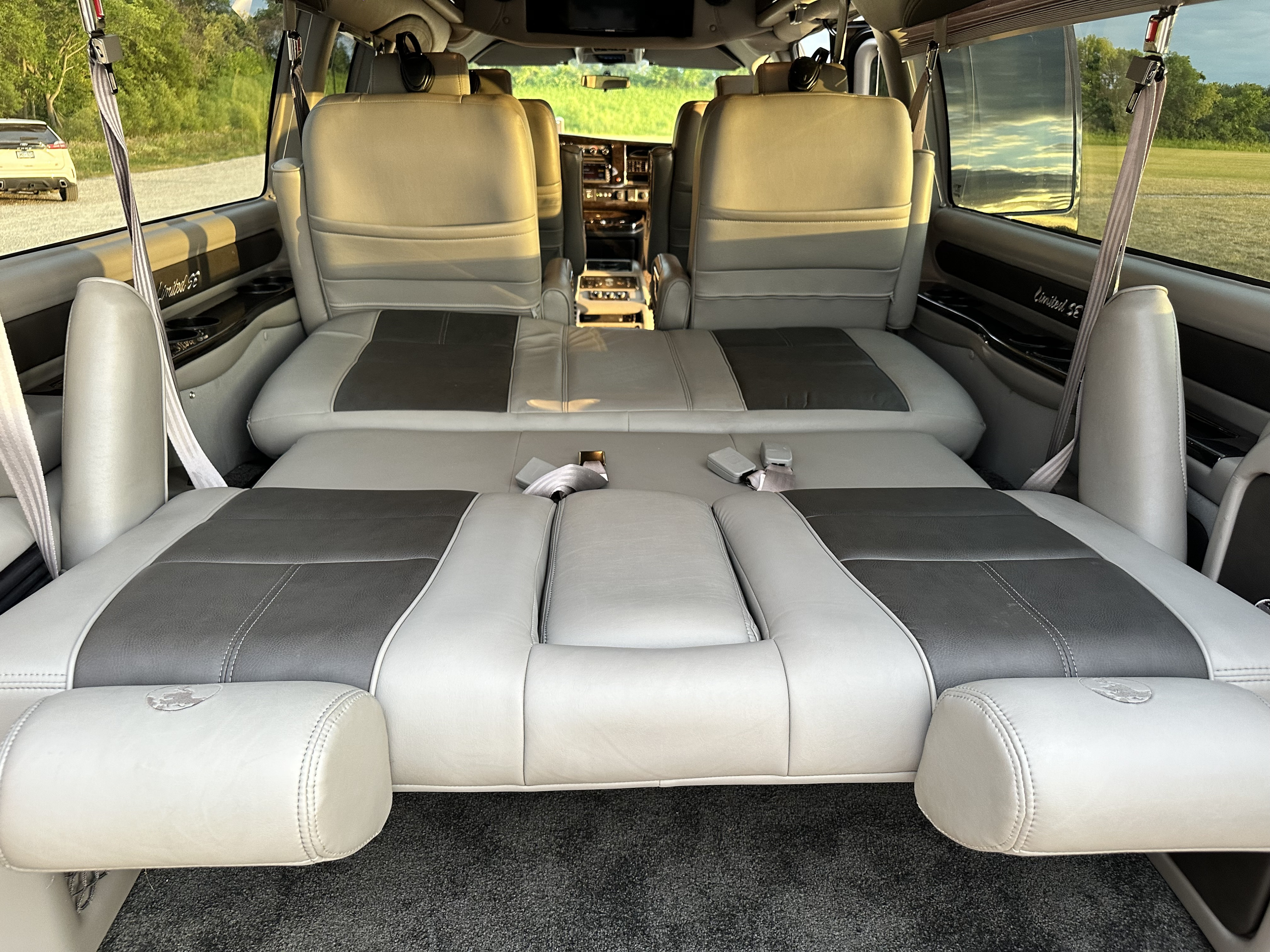 View inside an RV rental showing two-tone gray leather seats folded down to create a comfortable, spacious bed.. Gmc K2500 2017