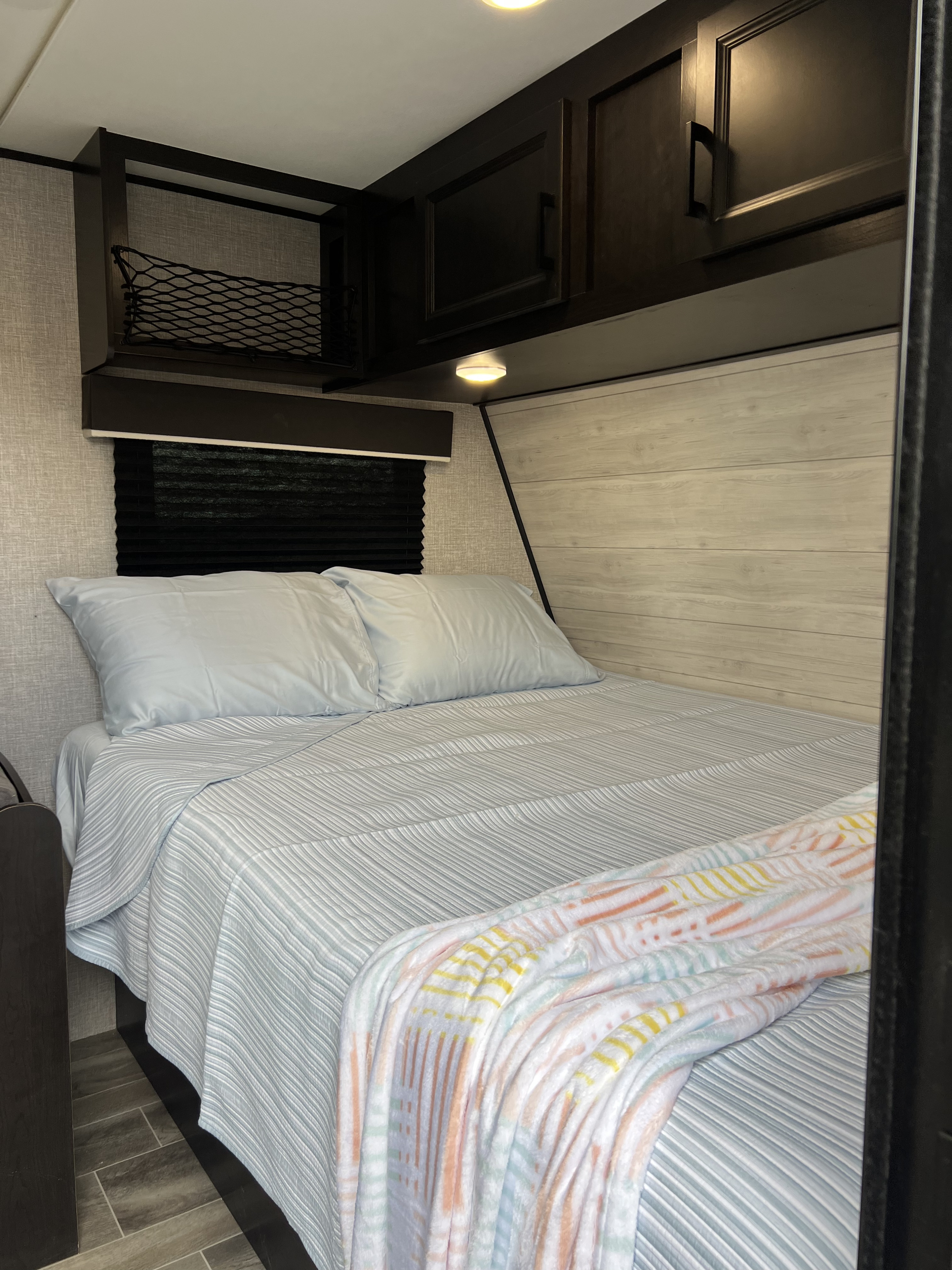 RV rental bedroom: A cozy space with a striped bed, light blue pillows, overhead storage, and a vibrant throw blanket.. Jayco Jay Flight SLX 2022