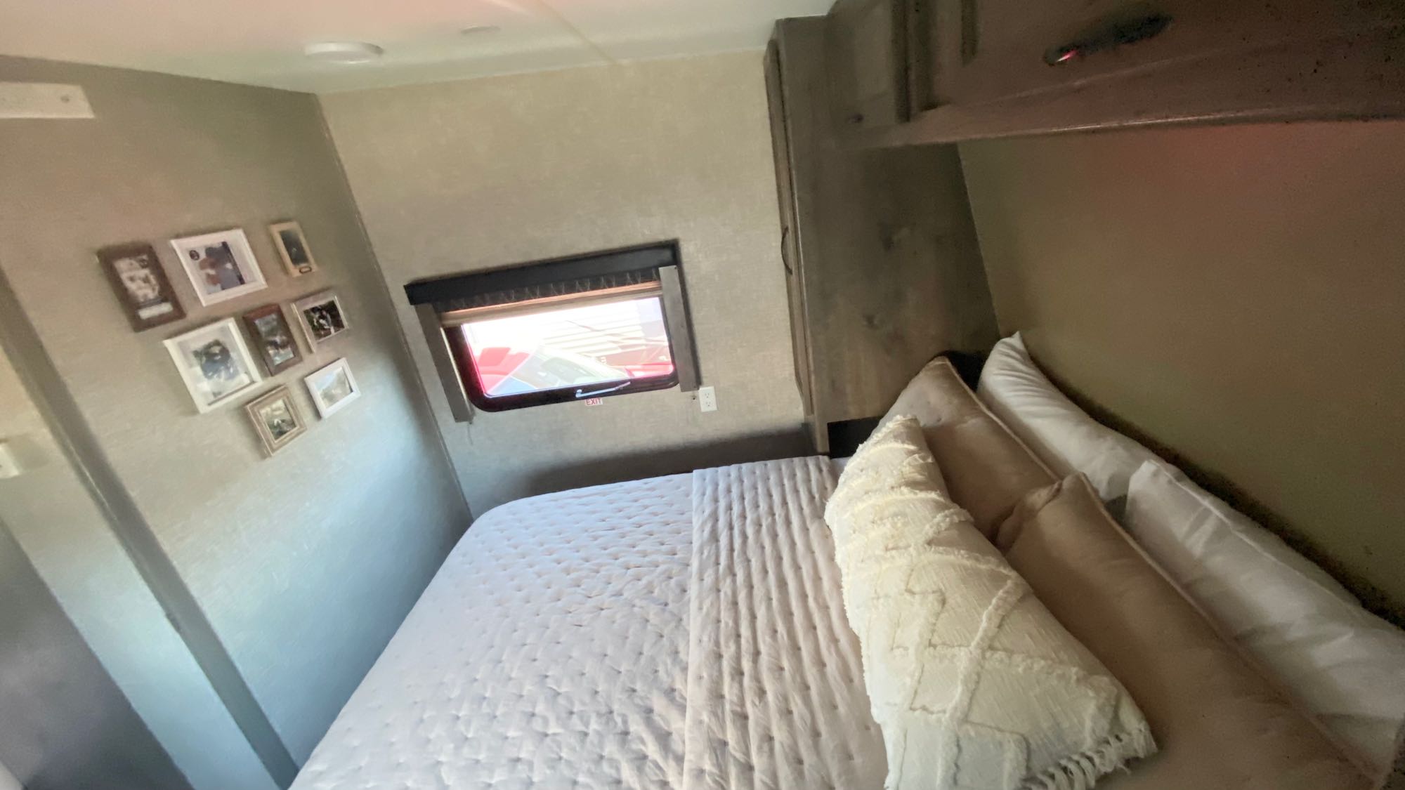 Cozy RV rental bedroom featuring a comfy bed, overhead cabinets, window, and wall decorated with framed photos.. Eclipse Recreational Vehicles Attitude 2016