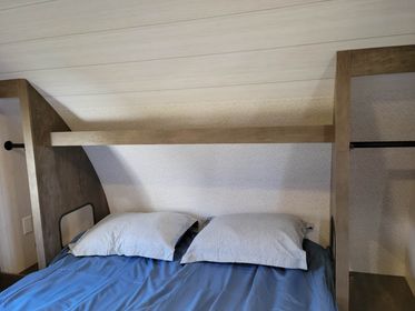 Inviting RV rental bedroom: bed with blue sheets, pillows, and integrated storage for your next adventure.. Forest River Wildwood X-Lite 2022
