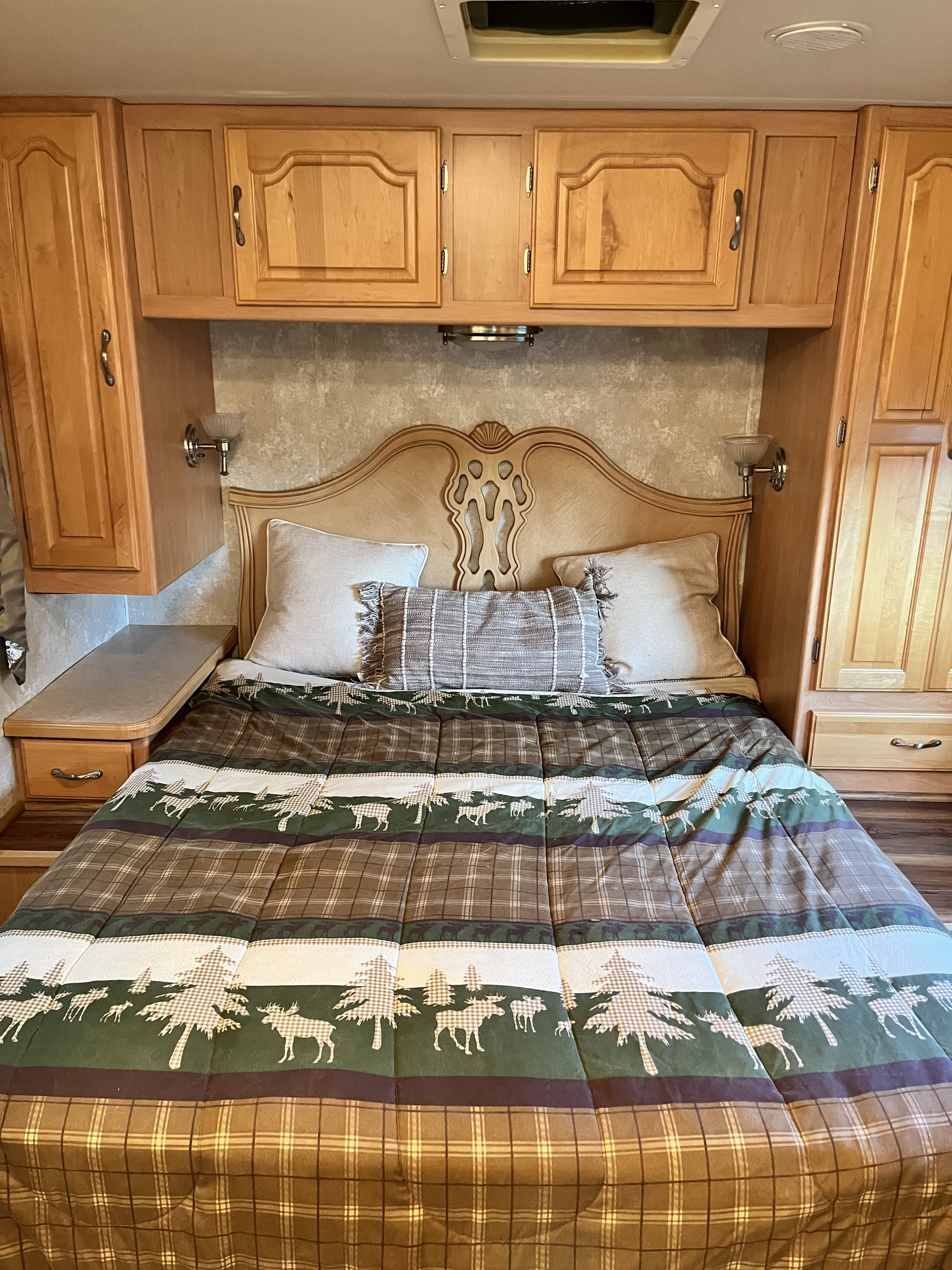 RV rental: Cozy bedroom with a full bed, patterned plaid/moose comforter, ornate headboard, and built-in wood cabinets.. Coachmen Santara Deluxe/Premier 2004