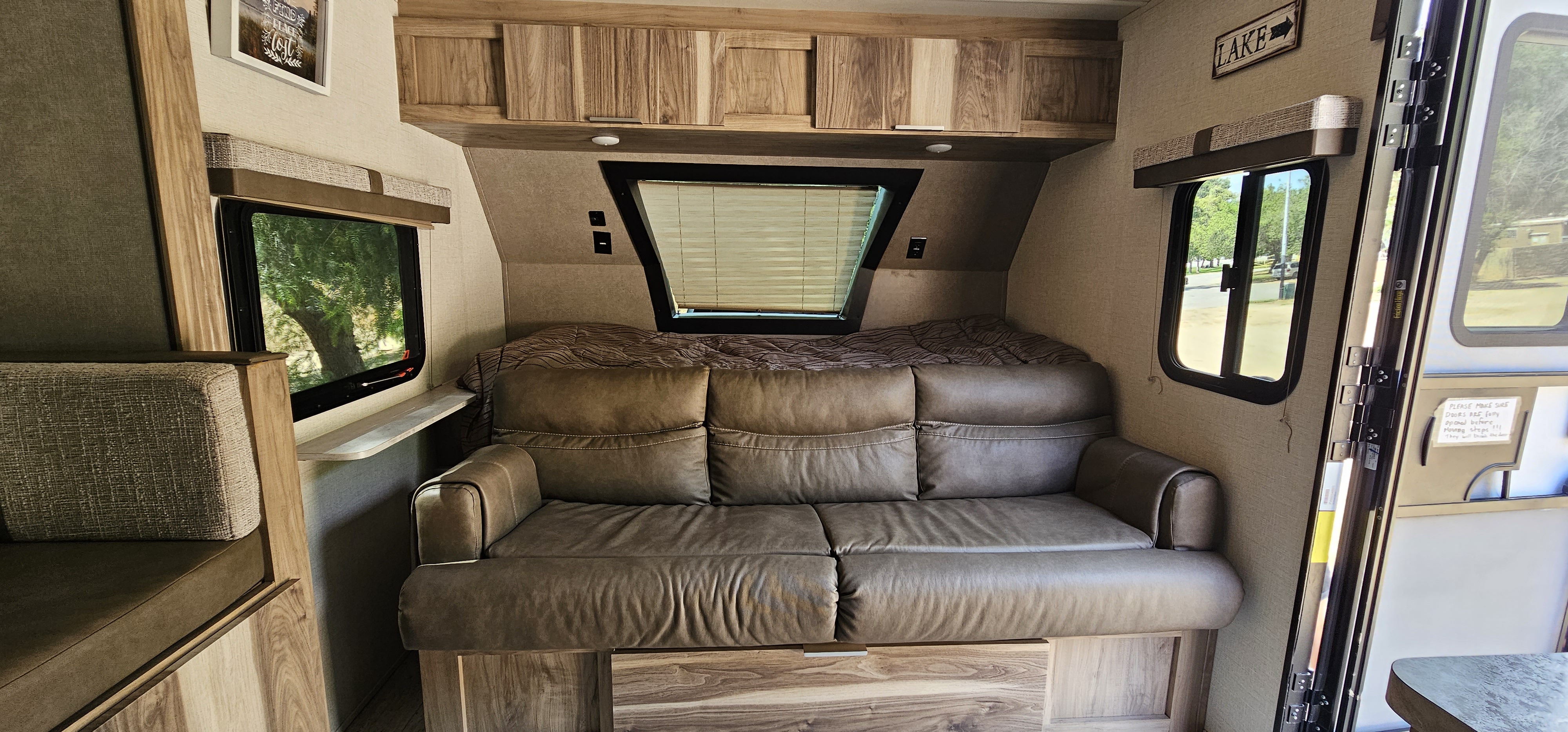 Cozy RV rental interior with a leather sofa, separate bed, and dinette, offering scenic window views.. Forest River Palomino Real-Lite Mini 2021