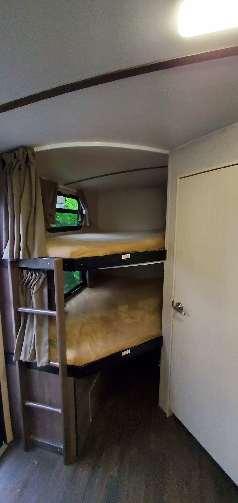 An RV rental's sleeping area, showing two bunk beds with mattresses, windows, and a ladder for convenient access.. Winnebago Winnebago Minni Plus 27BHSS 2018