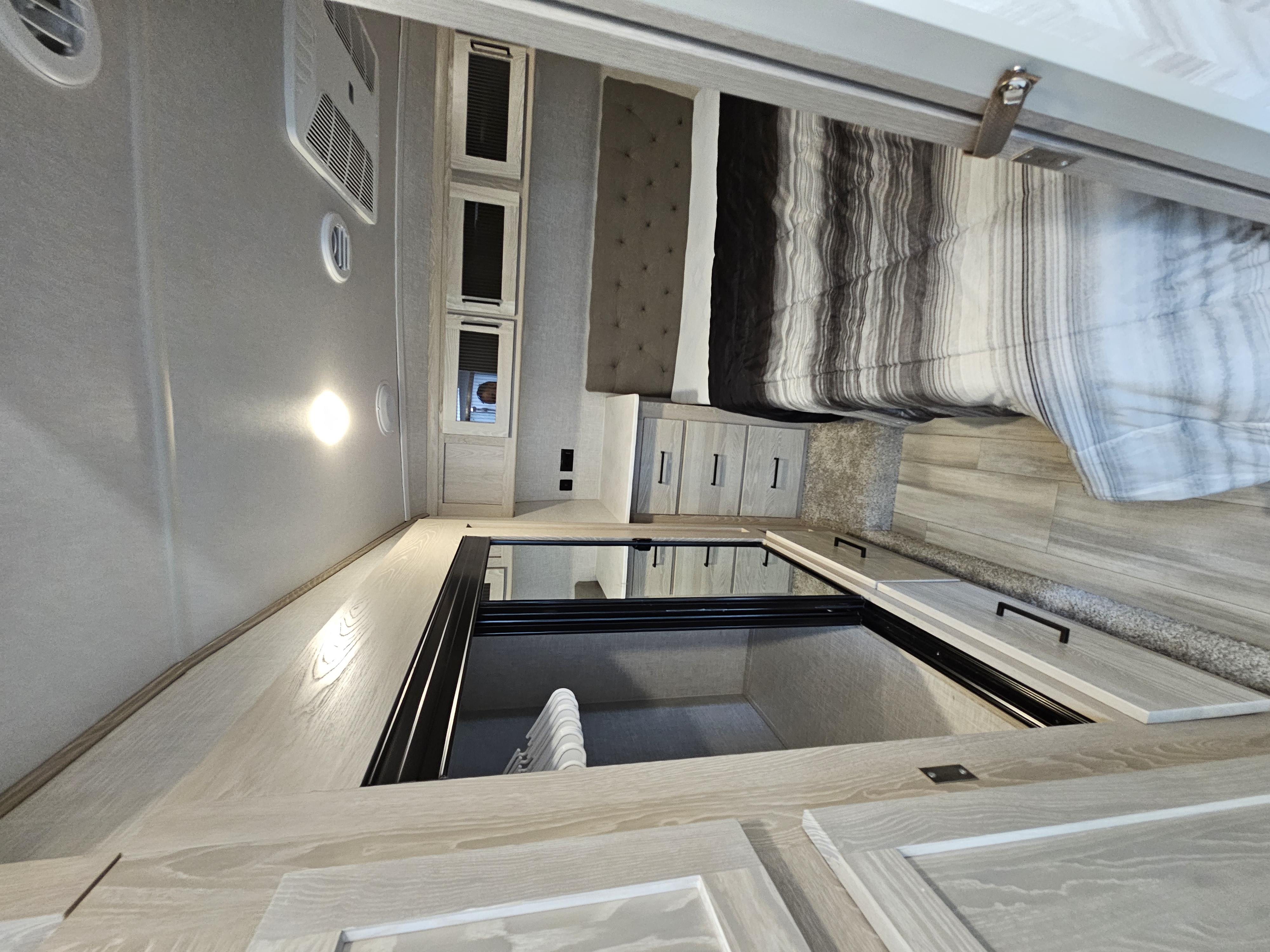 RV rental bedroom interior, showcasing a bed, nightstands, and ample built-in floor storage with hangers.. Forest River Flagstaff Super Lite 2022