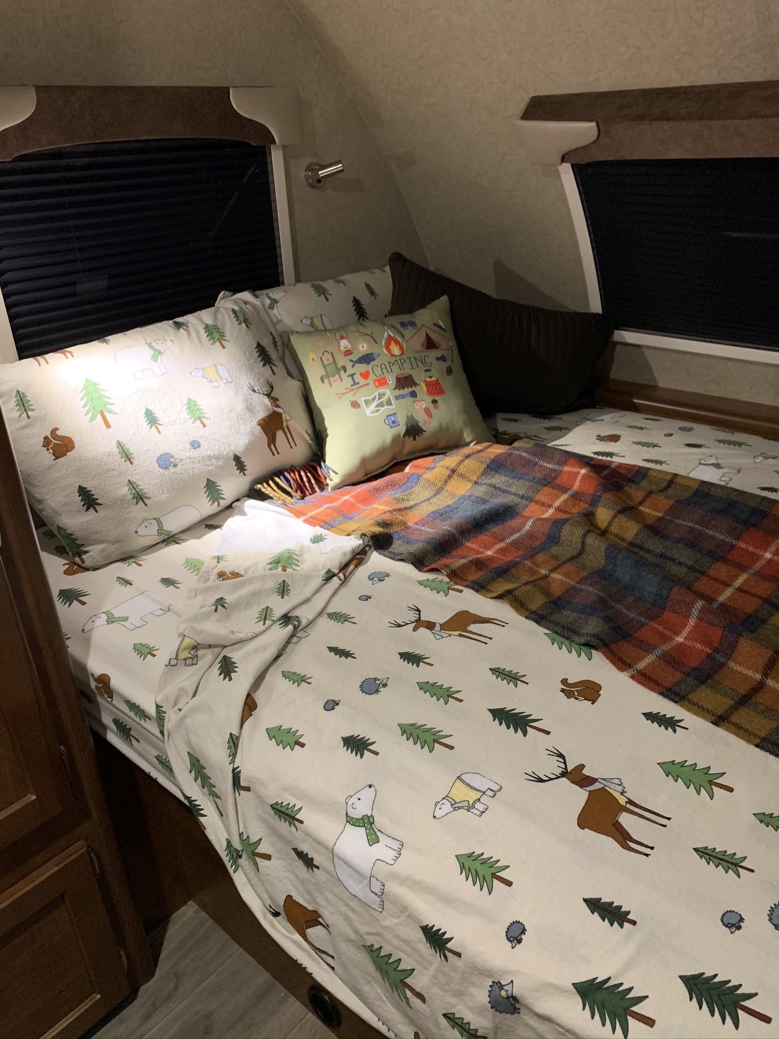Cozy RV rental bedroom with whimsical nature-themed bedding, a warm plaid blanket, and closed window blinds.. Lance Manufacturing Lance Manufacturing Trailer 2020