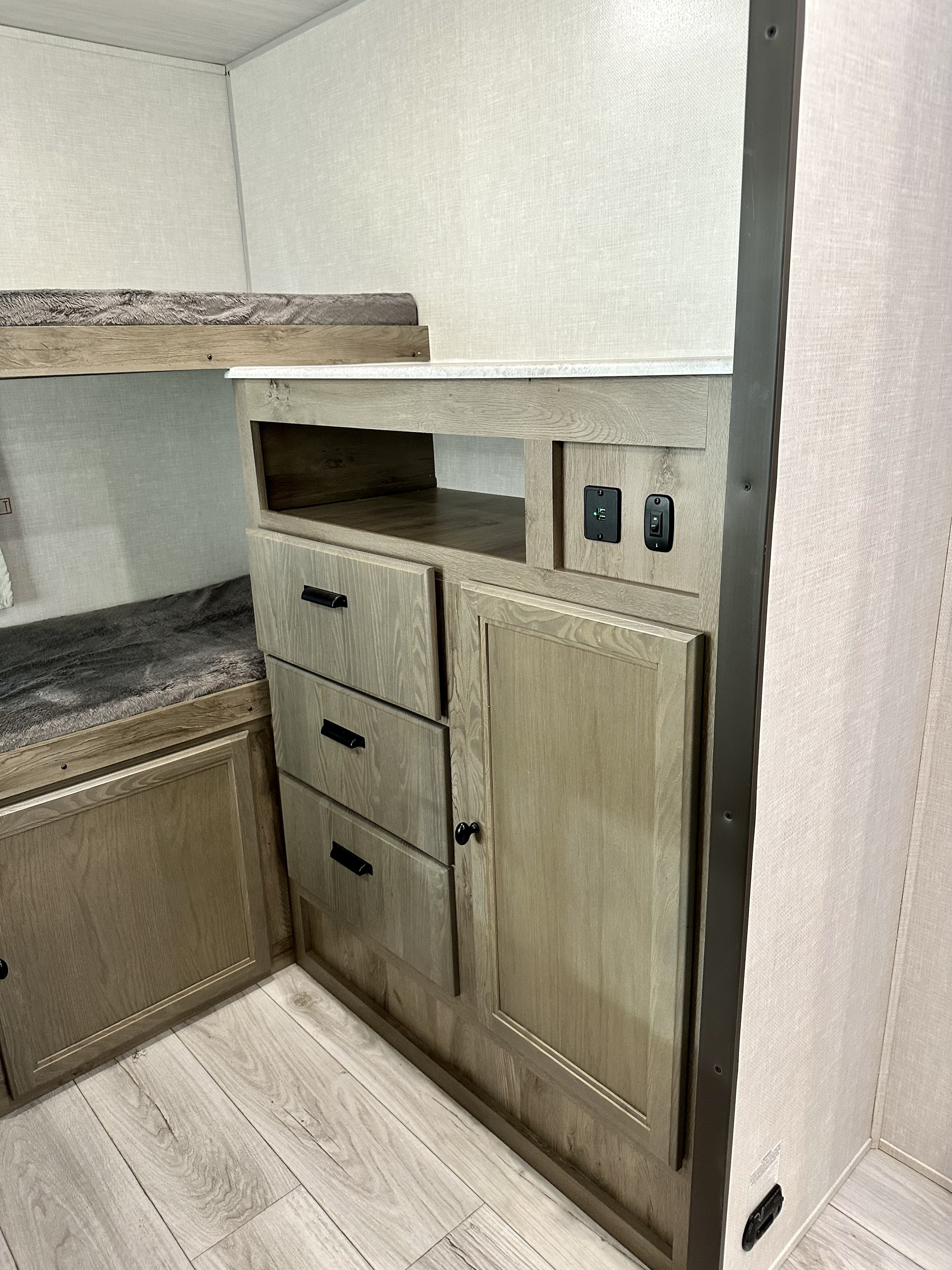 Cozy RV rental bunk area with light wood storage, USB charging, and plush bedding. Ideal for travel accommodation.. Forest River Surveyor Legend 2022