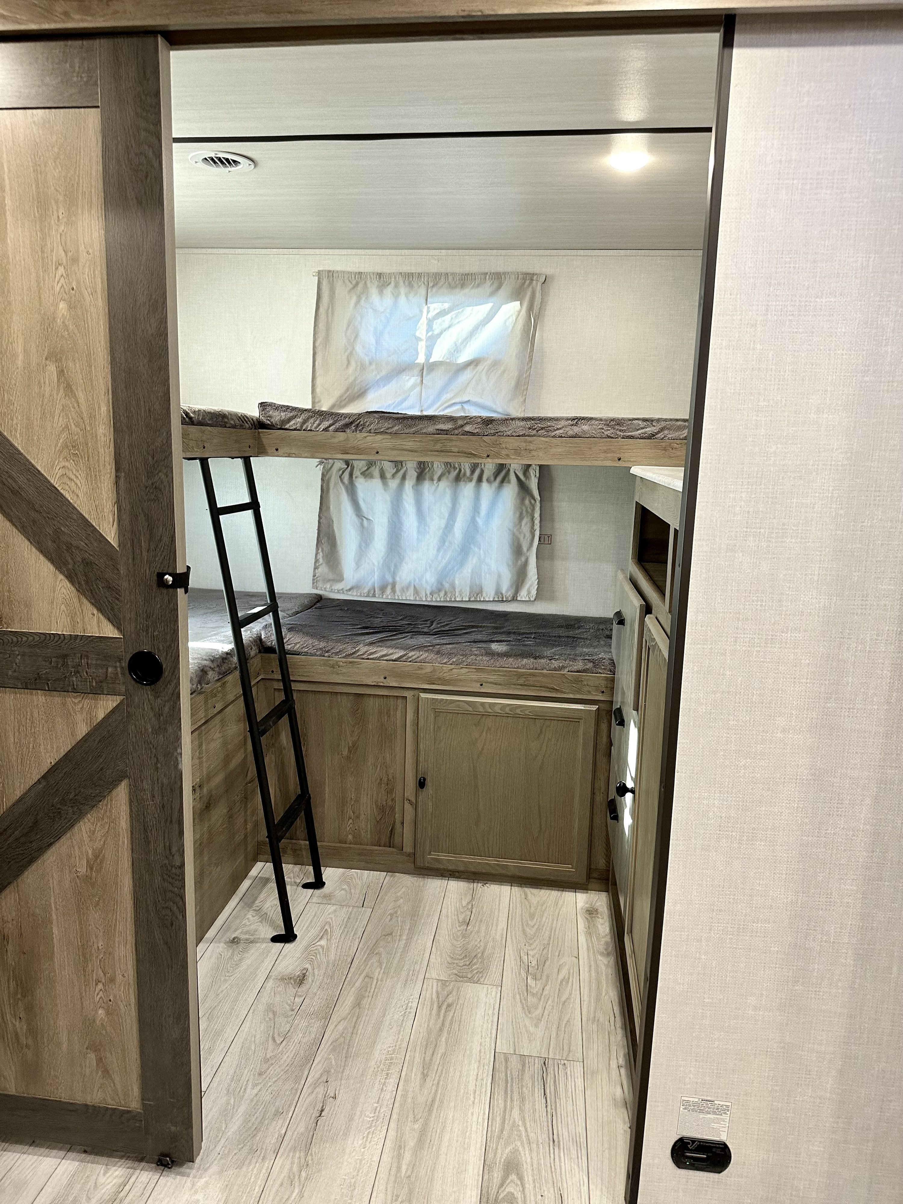 RV rental interior: a bunk room with two beds, ladder, light wood accents, ideal for family trips.. Forest River Surveyor Legend 2022