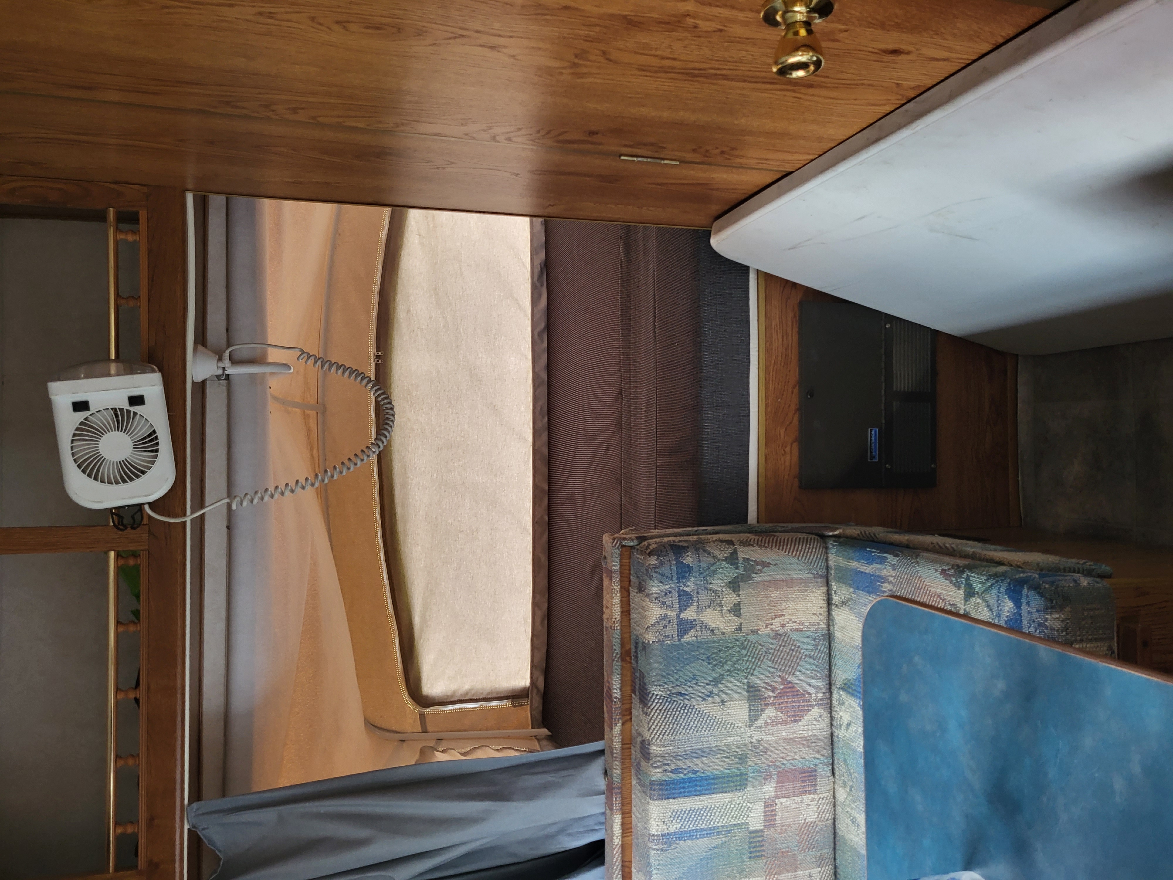 Cozy RV rental interior: white fan, canvas wall, patterned seating, and blue table, offering comfortable travel.. Aerolite Kodiak 2000