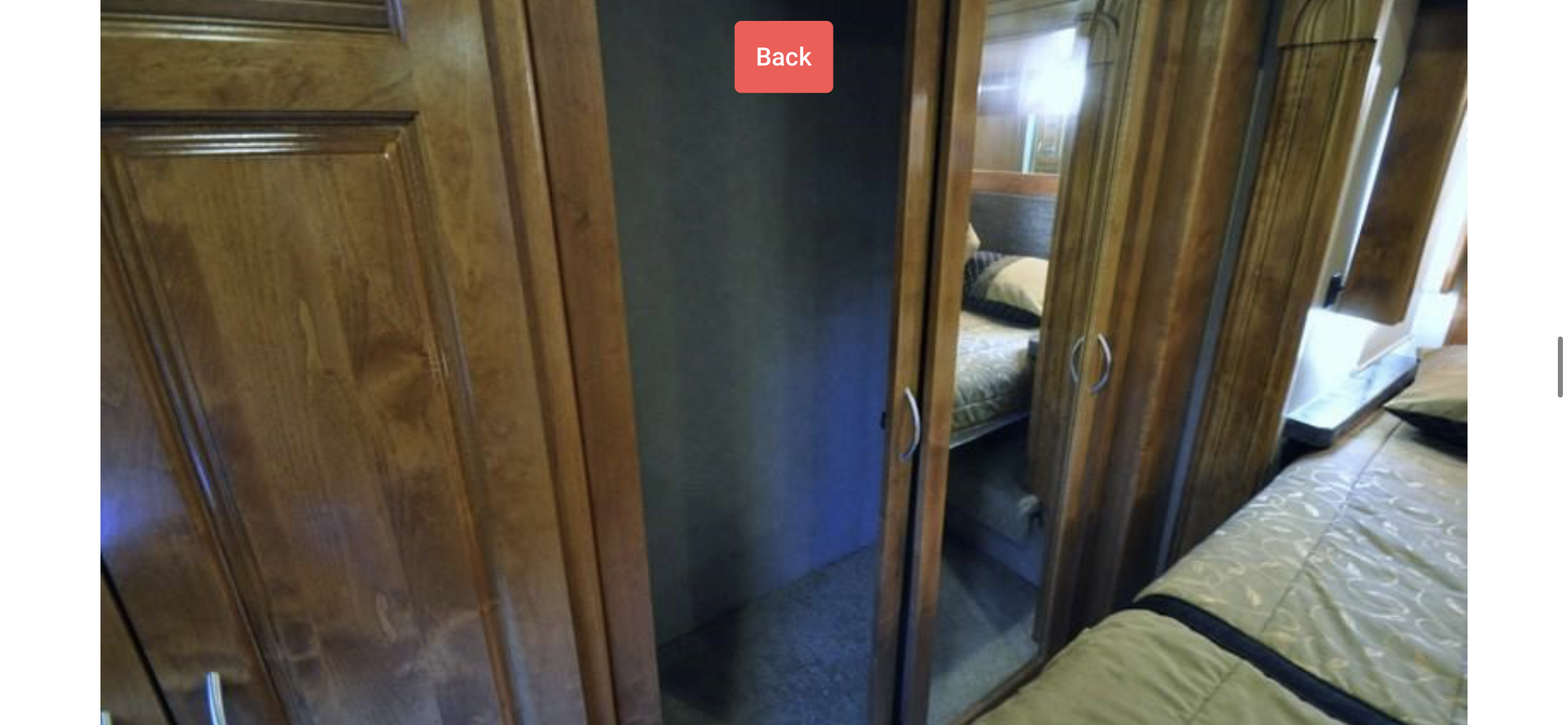RV rental interior showing a compact bedroom with wood cabinetry, open closet, and a mirrored wardrobe door reflecting the bed.. Monaco Vesta 2012