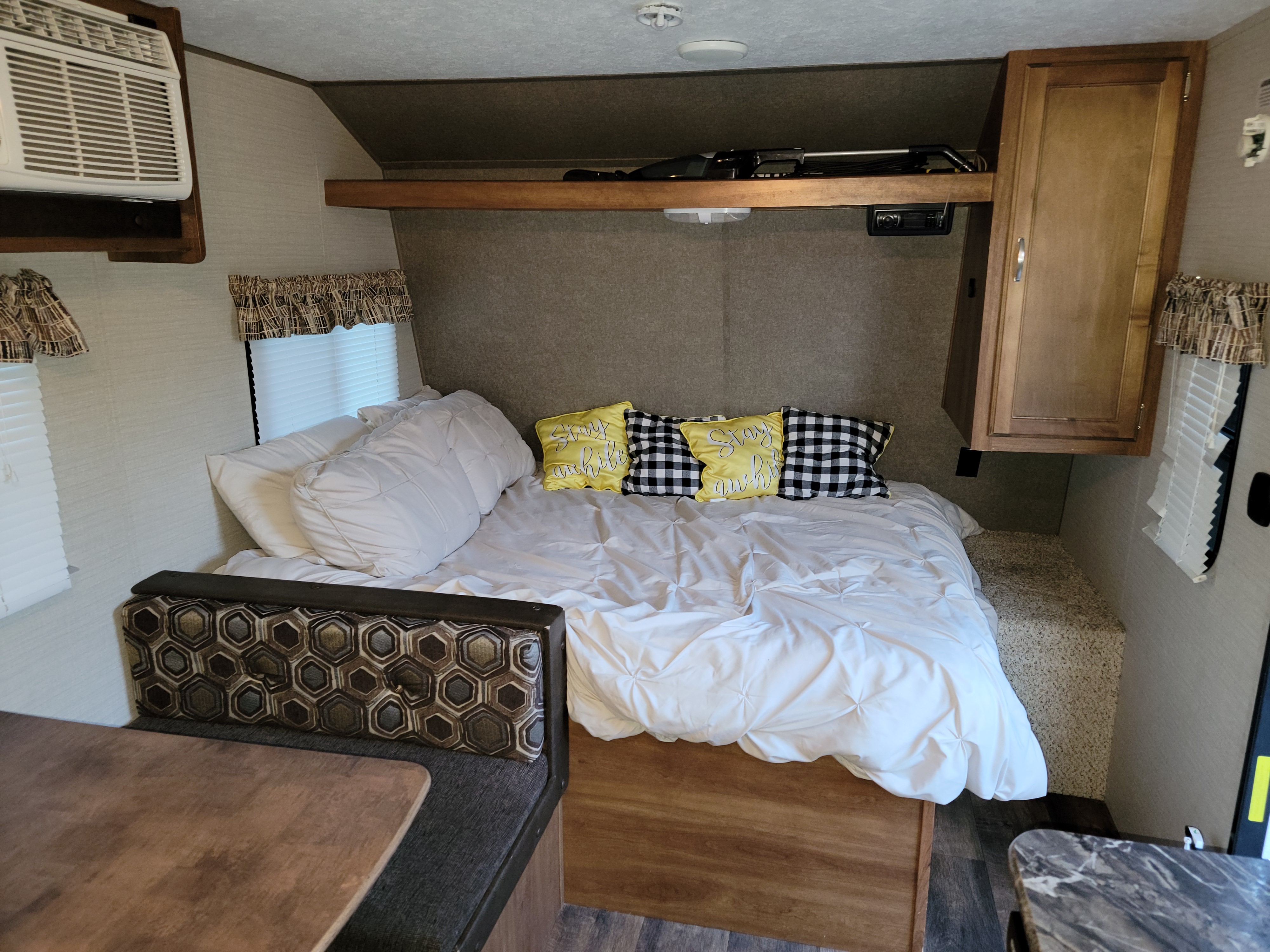 Cozy RV rental interior with a comfortable bed, dinette, and AC unit. Perfect for travel.. Keystone RV Summerland Mini 2016