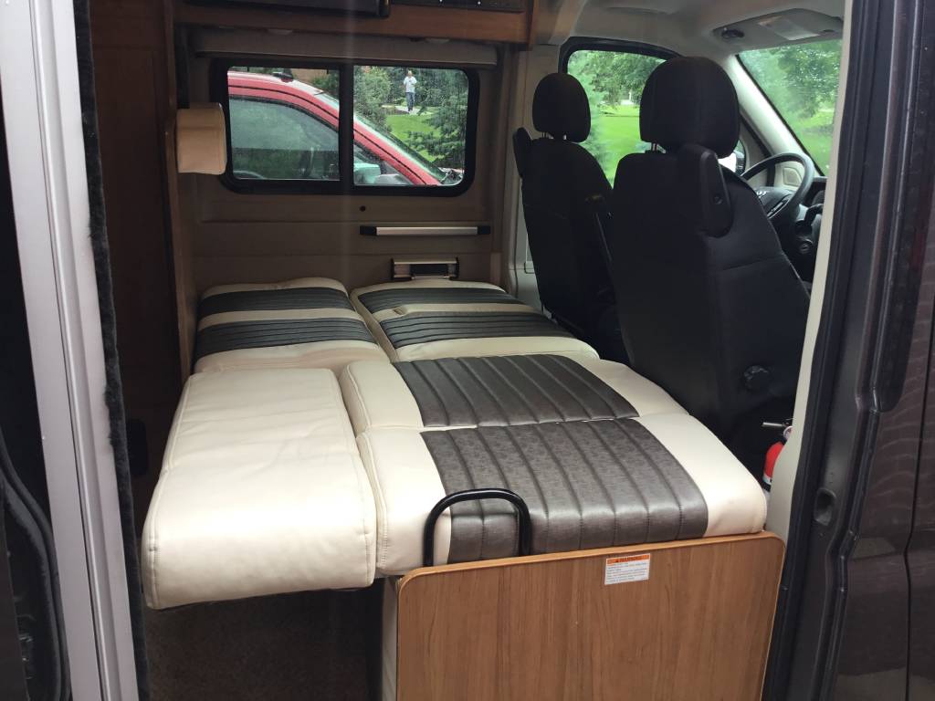 **RV rental** interior with convertible striped beds and black rotating front seats, ready for adventure.. Winnebago Travato 2017