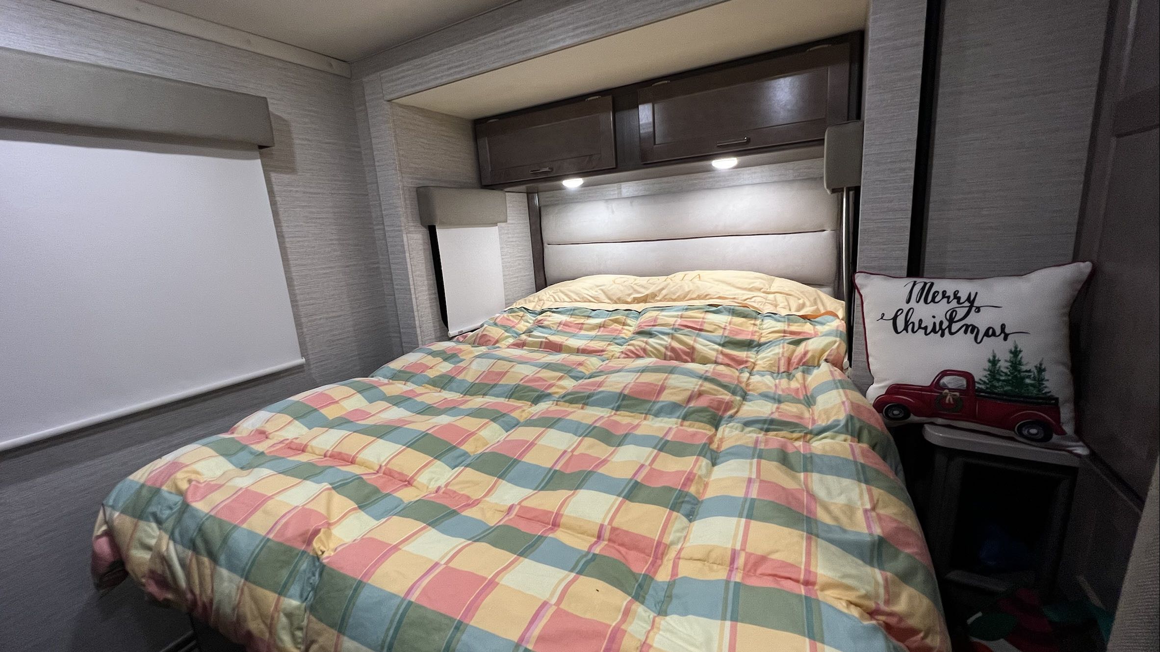 Relax in this cozy RV rental bedroom. Features a comfortable bed with plaid comforter, lighting, and holiday accents.. Winnebago Minnie Winnie 2022