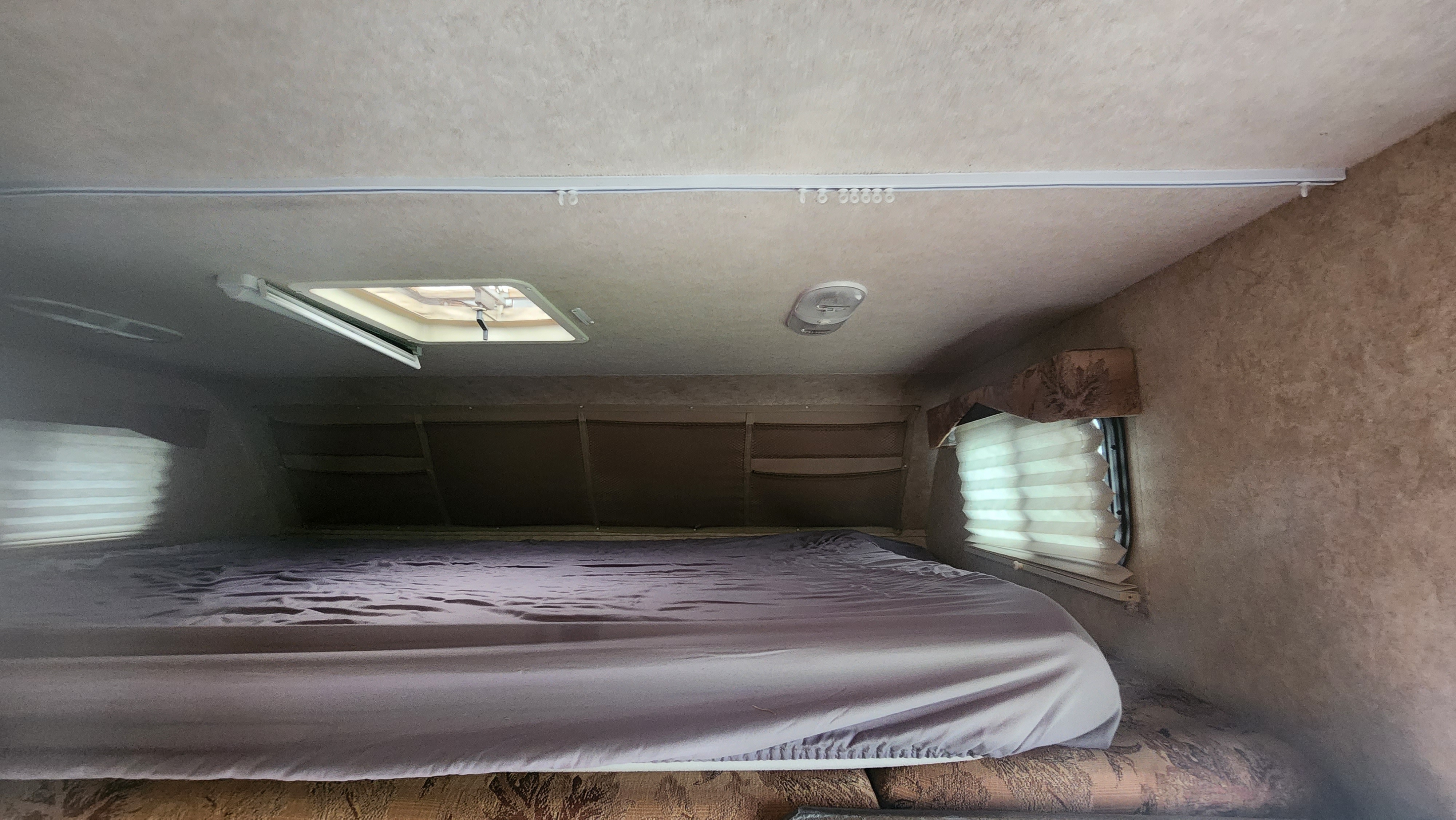 RV rental sleeping area: Overhead view of a bed with light sheets, ceiling light, and window blinds.. Adventurer Adventurer Motorhome 2014