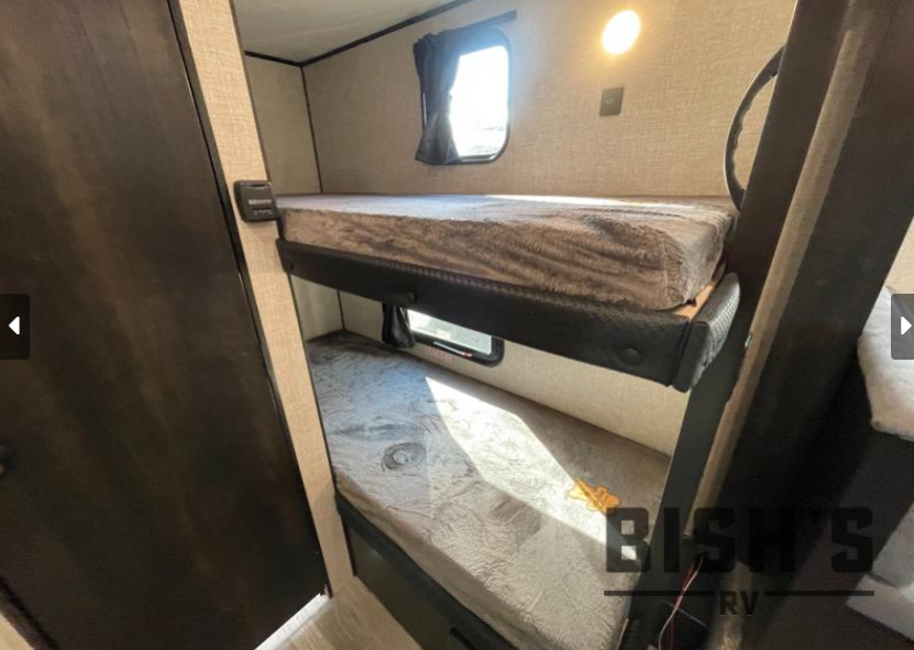 Interior of an RV rental showing bunk beds with mattresses, windows, and light. A compact and functional sleeping area.. Jayco Jay Flight SLX 2023