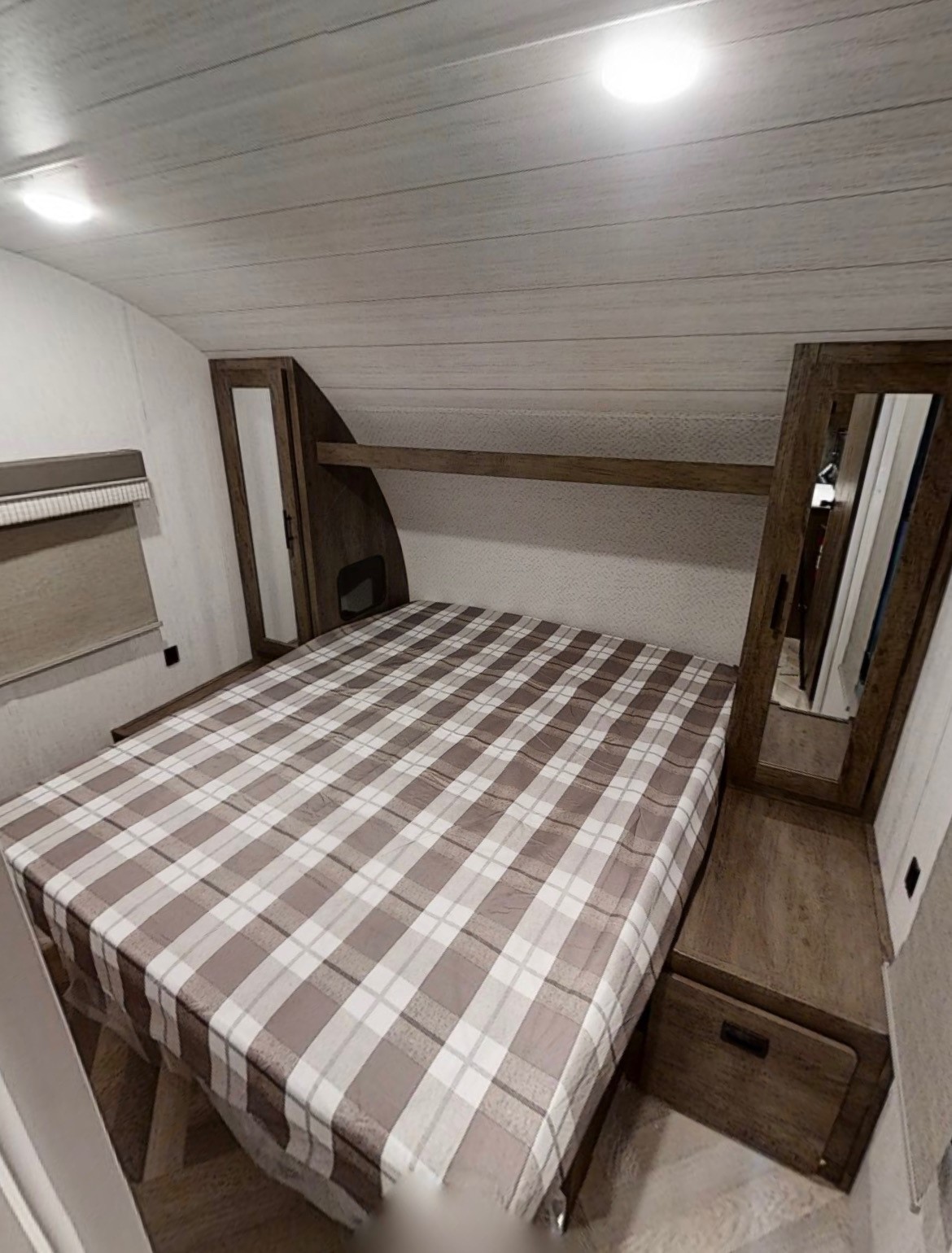 Cozy RV rental bedroom featuring a plaid bed, built-in storage, and bright lighting for your travels.. Forest River Salem Cruise Lite 2021