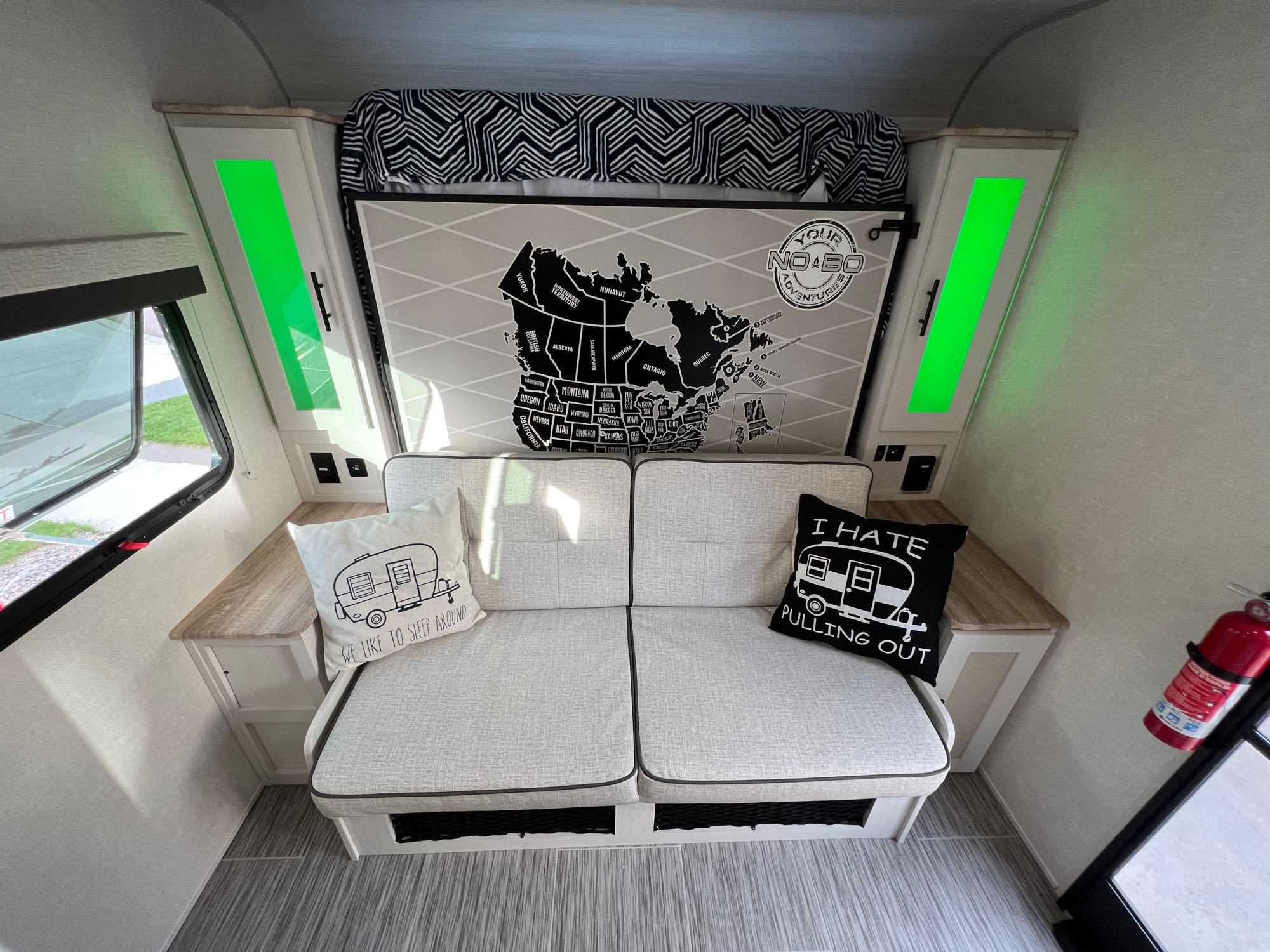 Explore this rv rental interior: cozy seating, illuminated storage, a North America map, and humorous travel pillows.. No Boundaries 19.3 2023