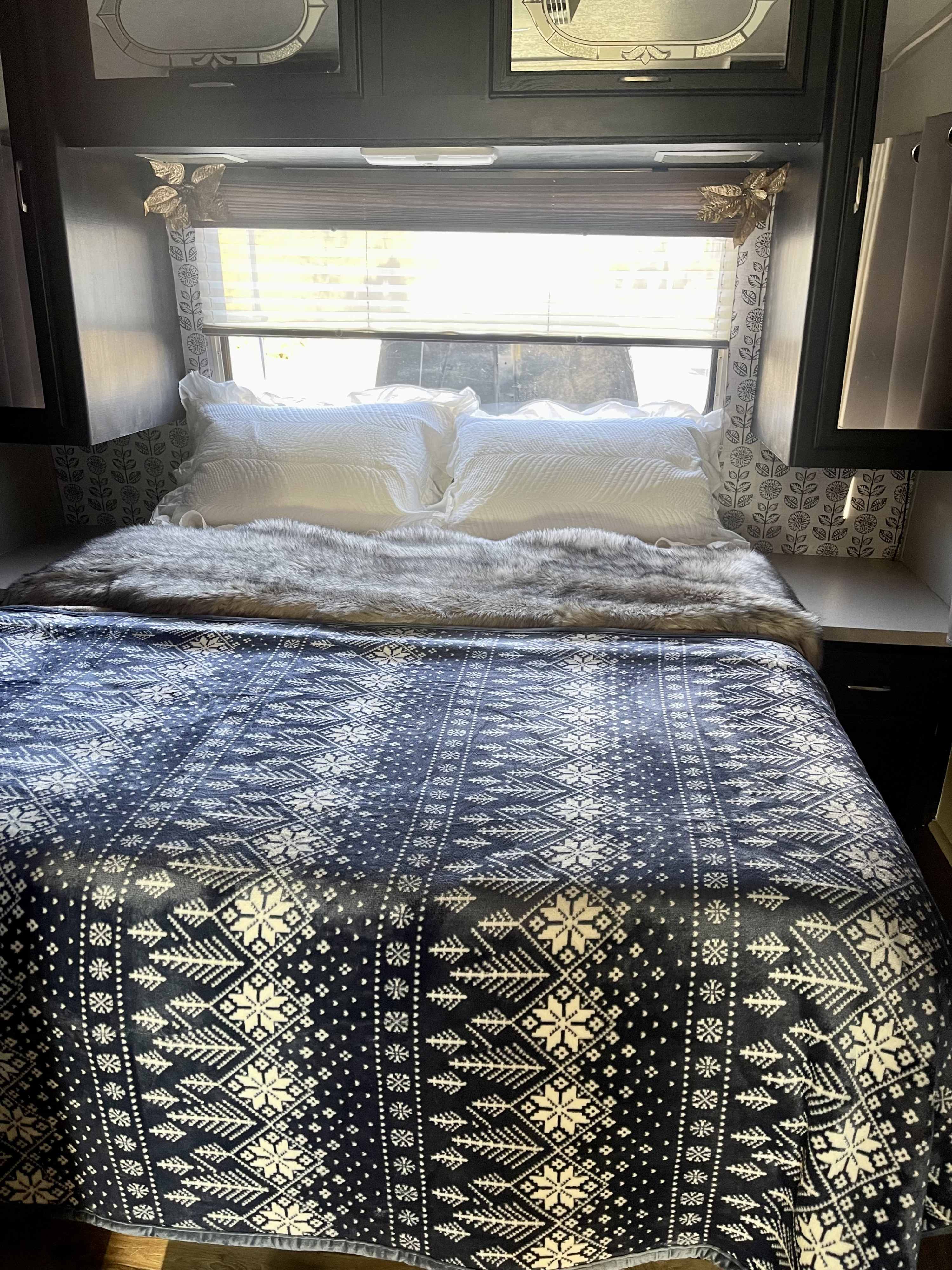 Cozy RV rental bedroom showcasing a bed with a festive Nordic blanket, soft pillows, and inviting decor.. Thor Motor Coach Four Winds Majestic 1996