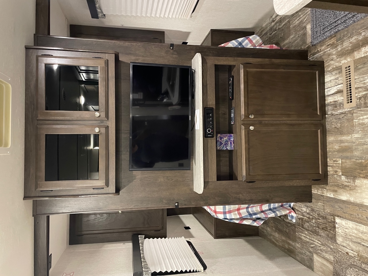 Modern RV rental interior featuring an entertainment unit with TV, dark wood cabinets, and built-in storage.. Starcraft Autumn Ridge Outfitter 2019