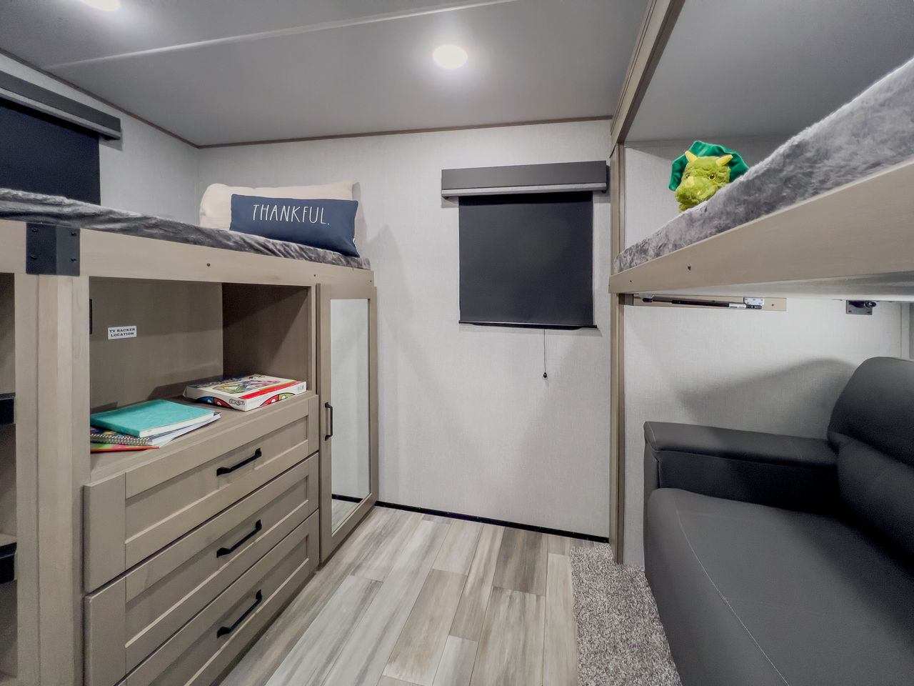 RV rental bunk room with comfy beds, built-in dresser storage, and a sofa for relaxing.. Grand Design Reflection 2023
