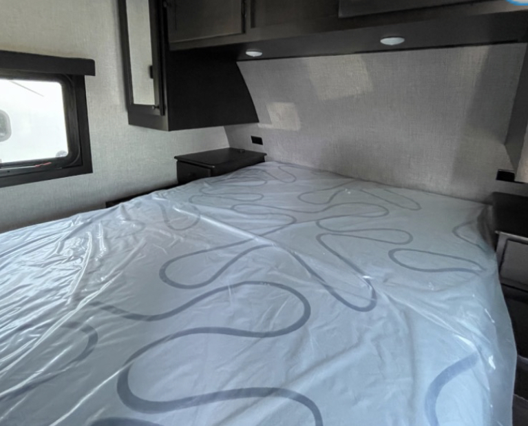 Spacious RV rental bedroom with a large bed (still in plastic), window, and overhead cabinets, ready for adventure.. Starcraft Super Lite 2023