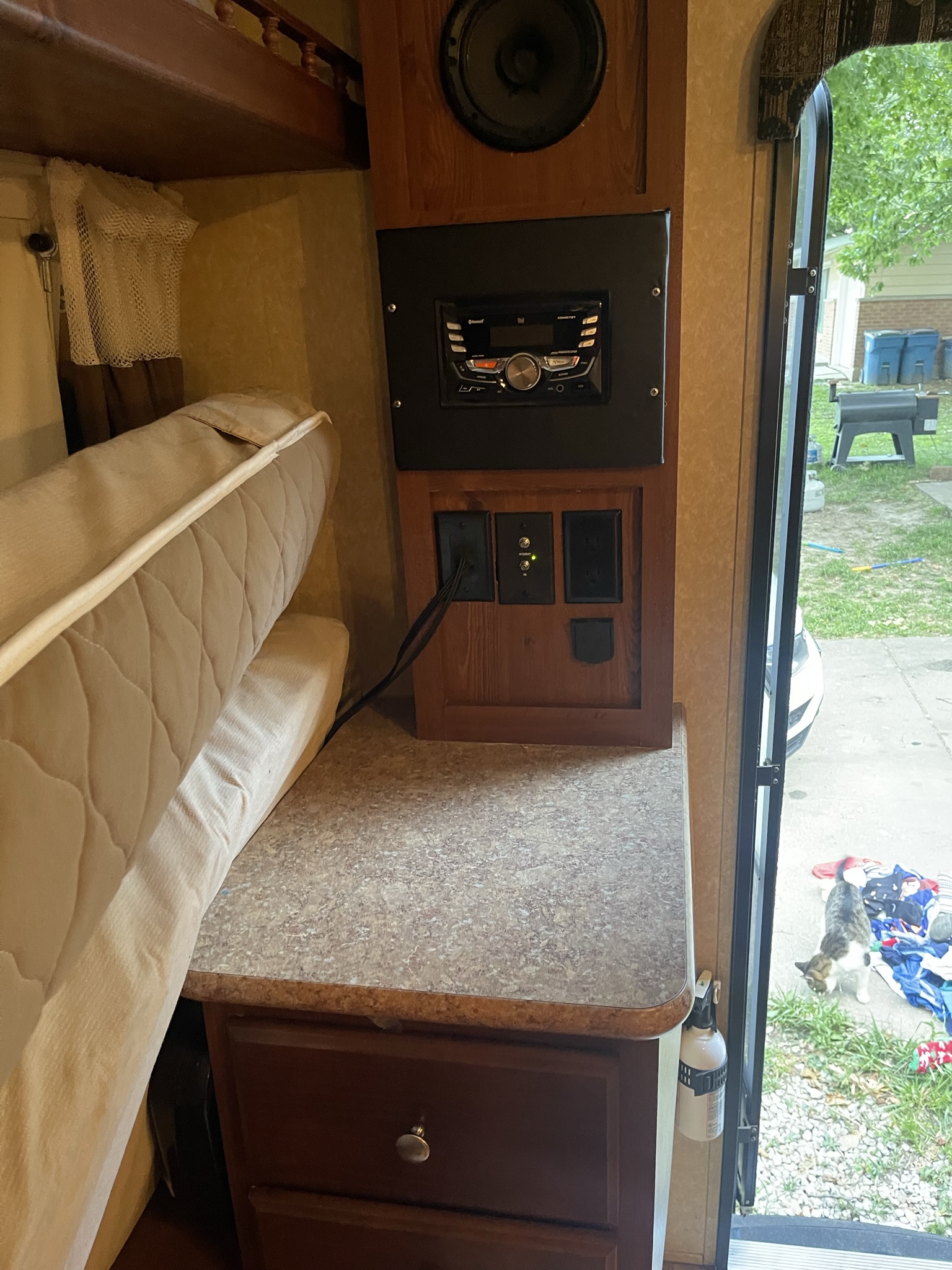 Inside an rv rental: features like a stereo, outlets, bunk bed, and countertop. A cat peeks in from the open door.. Forest River Rockwood Roo 2011
