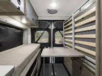 RV rental camper van interior: compact living space with a bed, central table, and versatile slatted wall, perfect for adventure.. Winnebago Solis 2023