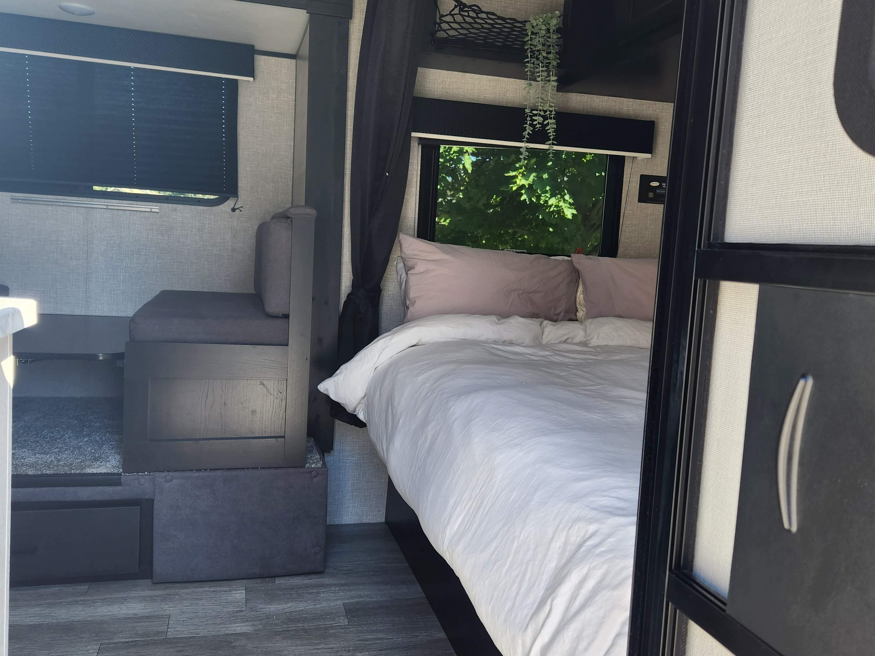 Comfortable RV rental interior: bedroom with pink pillows, white bedding, and a cozy dinette. Modern and compact.. Jayco Jay Flight SLX Baja Edition 2023